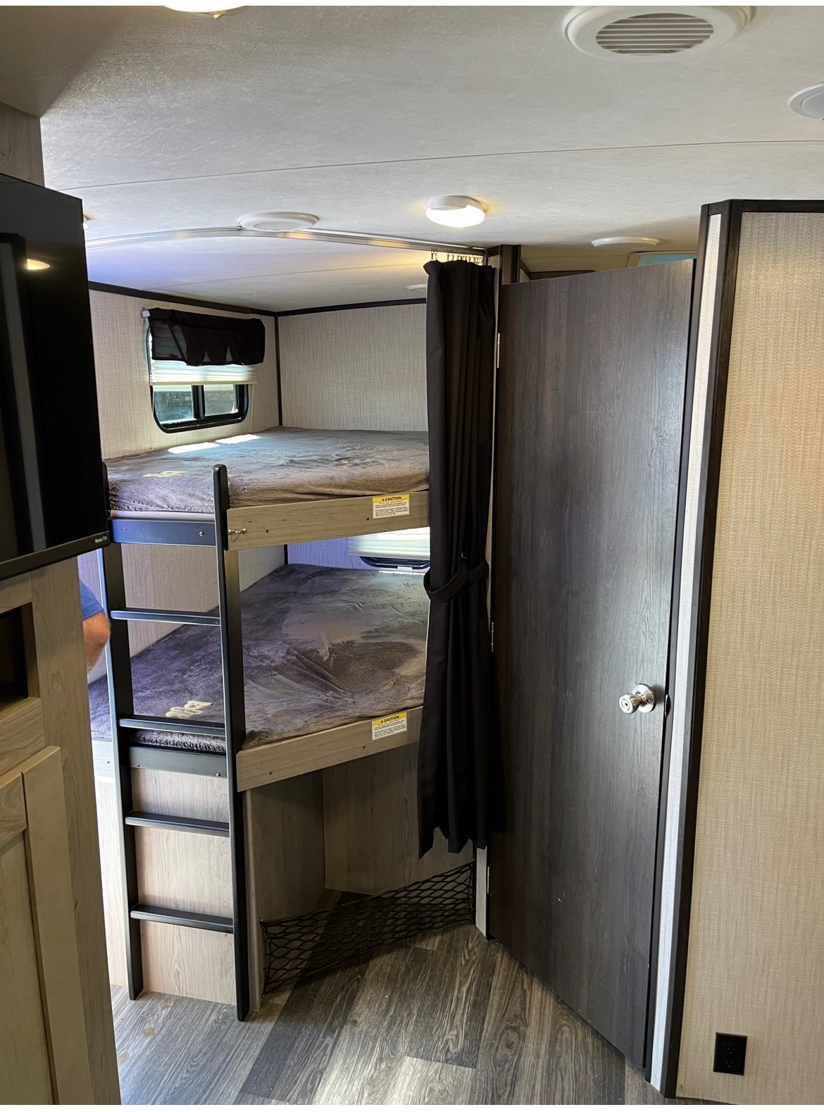 Inside an RV rental: A view of stacked bunk beds with a ladder, privacy curtain, and window. Ideal for family trips.. Heartland RVs Mallard 2021