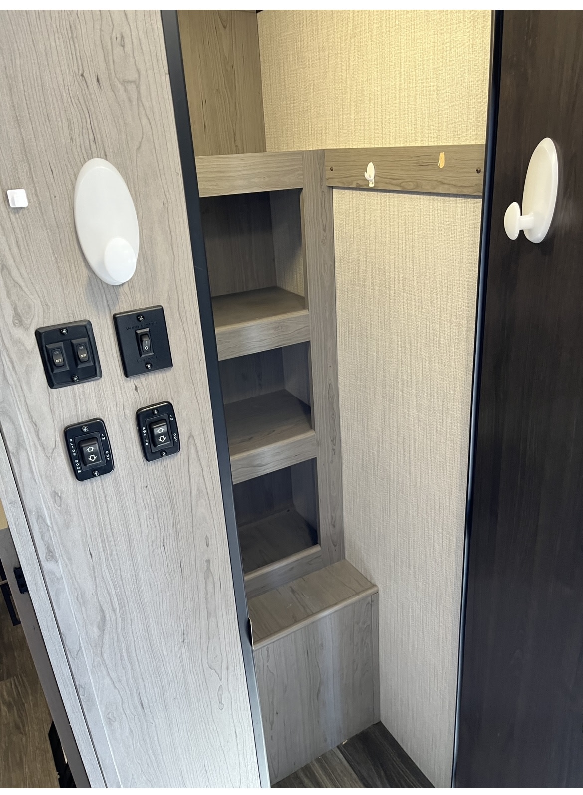 RV rental interior featuring an control panel with multiple switches, built-in storage shelves, and hooks.. Heartland RVs Mallard 2021