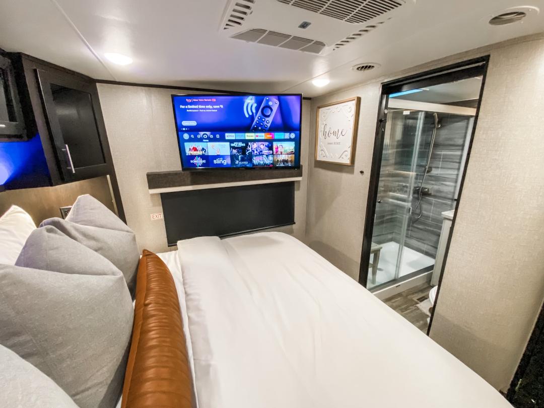 RV rental bedroom: cozy bed, TV, & glass shower create a comfy home on wheels.. Jayco Seismic Toy Hauler 2021