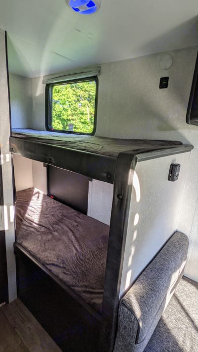 RV rental bunk beds: a cozy interior view with upper and lower berths, window, and plush blanket.. Cherokee wolf pup 2021