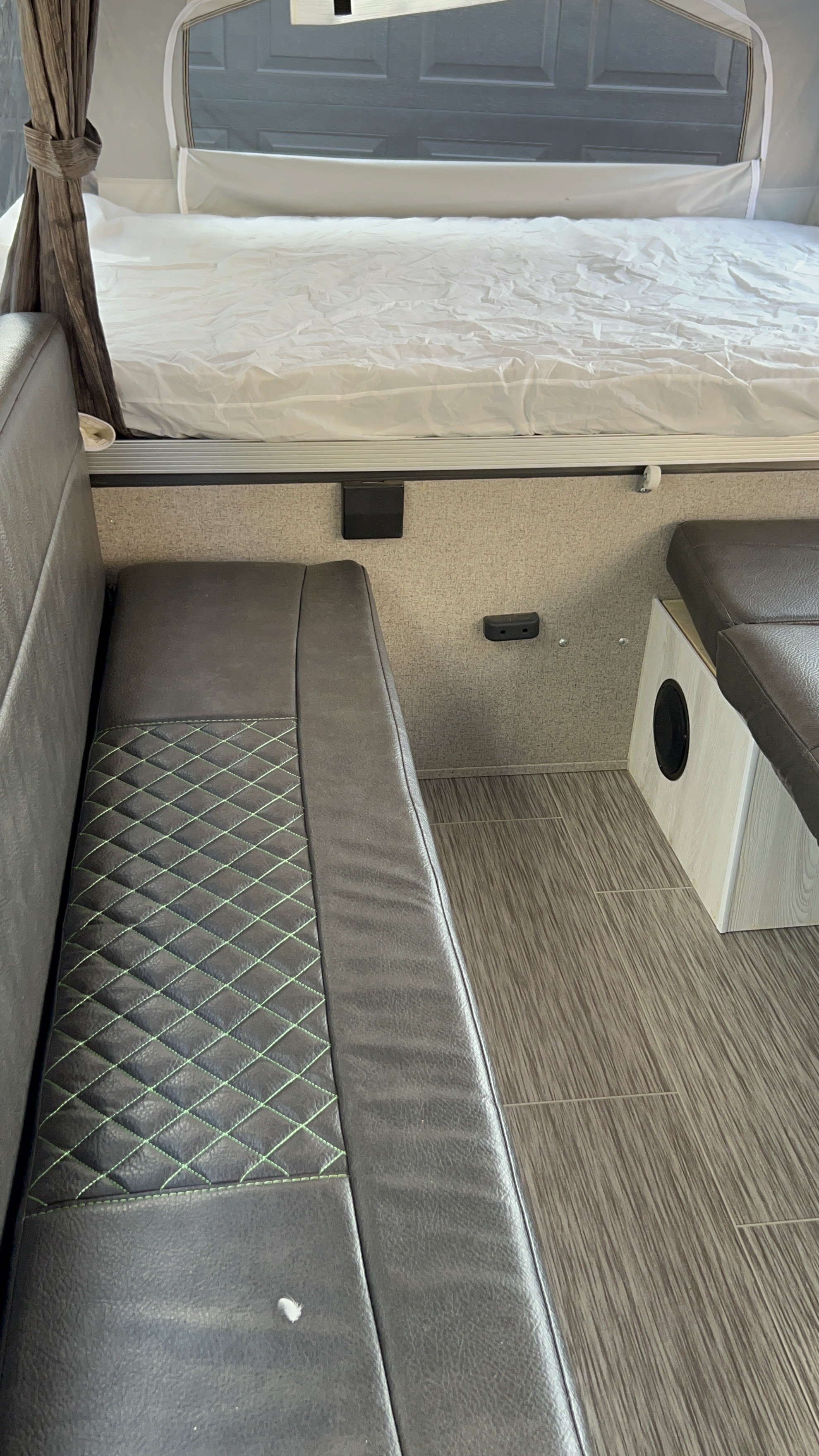 Comfortable RV rental interior featuring a neatly made bed, dinette seating with green stitching, and durable flooring.. Forest River Palomino Compass 2017