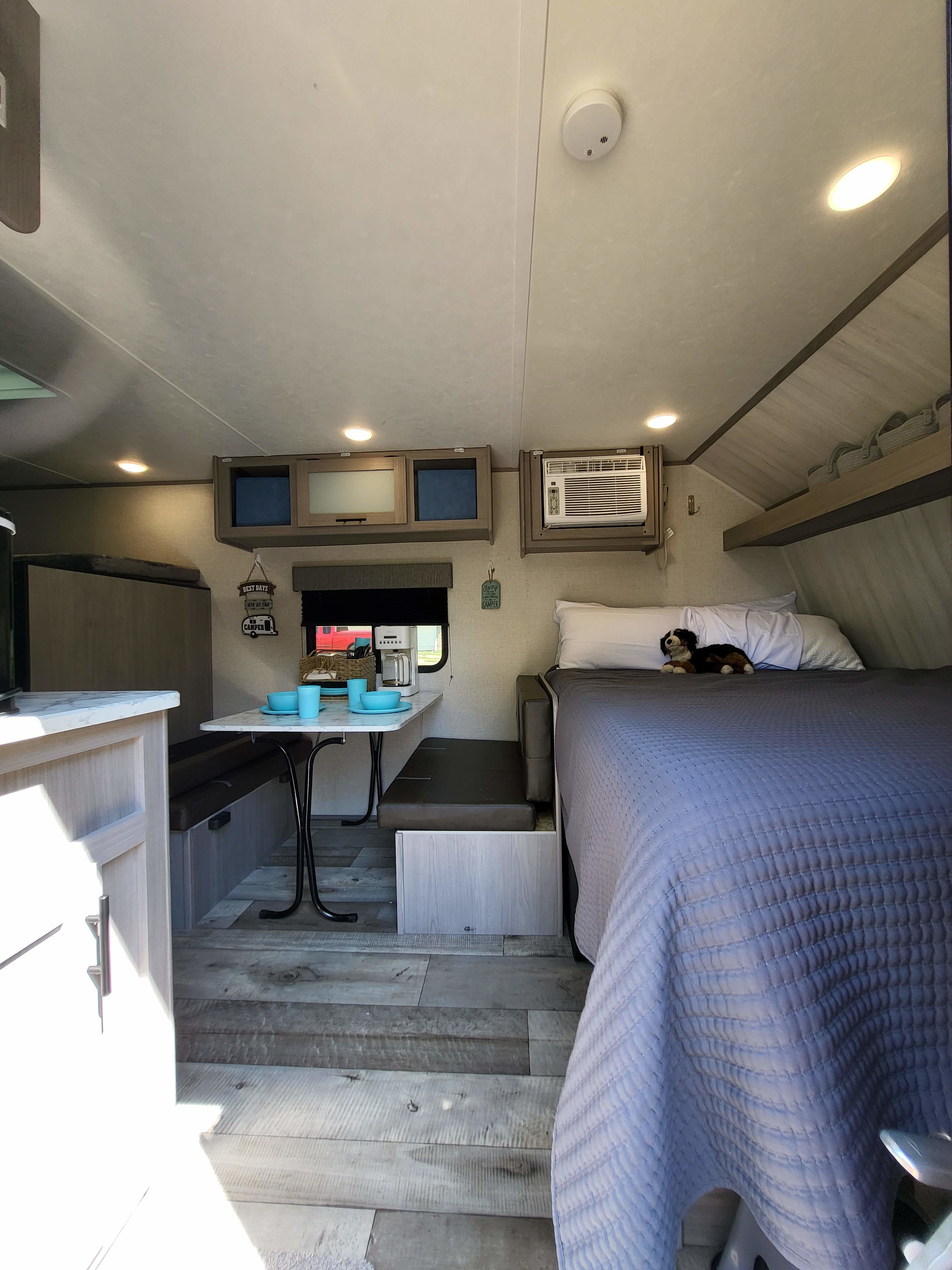 Cozy RV rental interior with a comfy bed, dinette area, kitchen, and overhead storage, ideal for travel adventures.. Dutchmen Coleman Lantern LT 2023