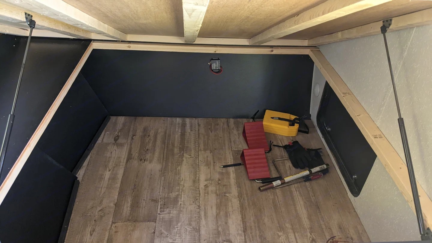 RV rental's spacious under-bed storage compartment with wood-look floor, red leveling blocks, and tools.. Cherokee wolf pup 2021