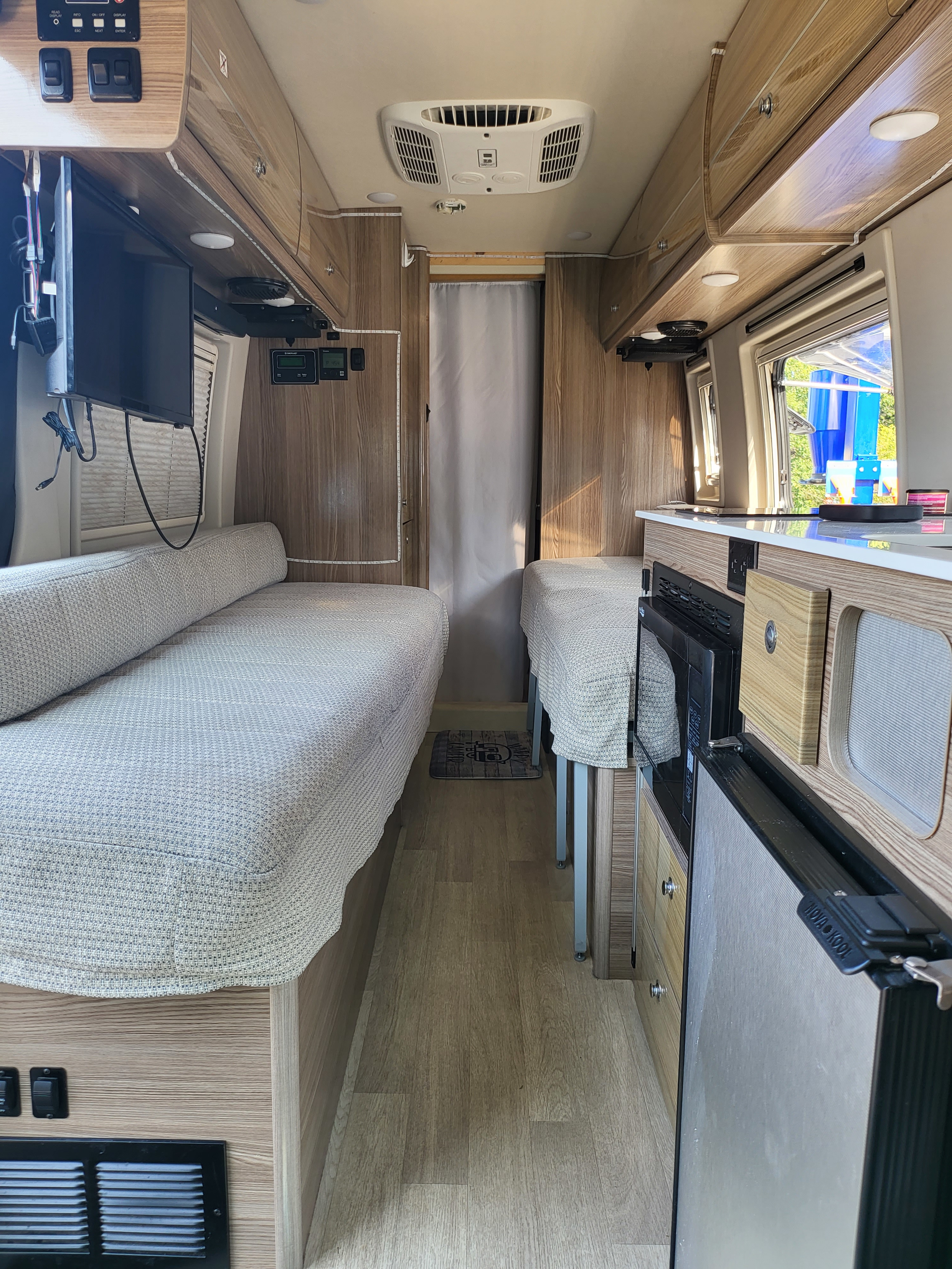 Explore this cozy rv rental interior featuring twin beds, a compact kitchen, and efficient storage solutions.. Winnebago Boldt 2020