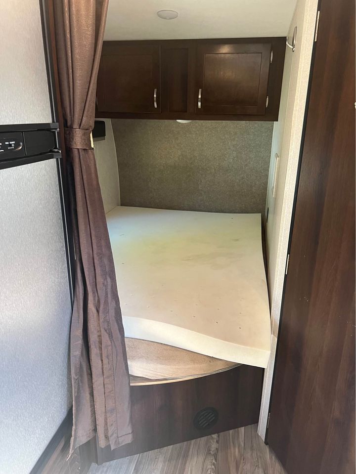RV rental bedroom view with foam mattress, overhead storage cabinets, and a privacy curtain.. Jayco Octane 2018