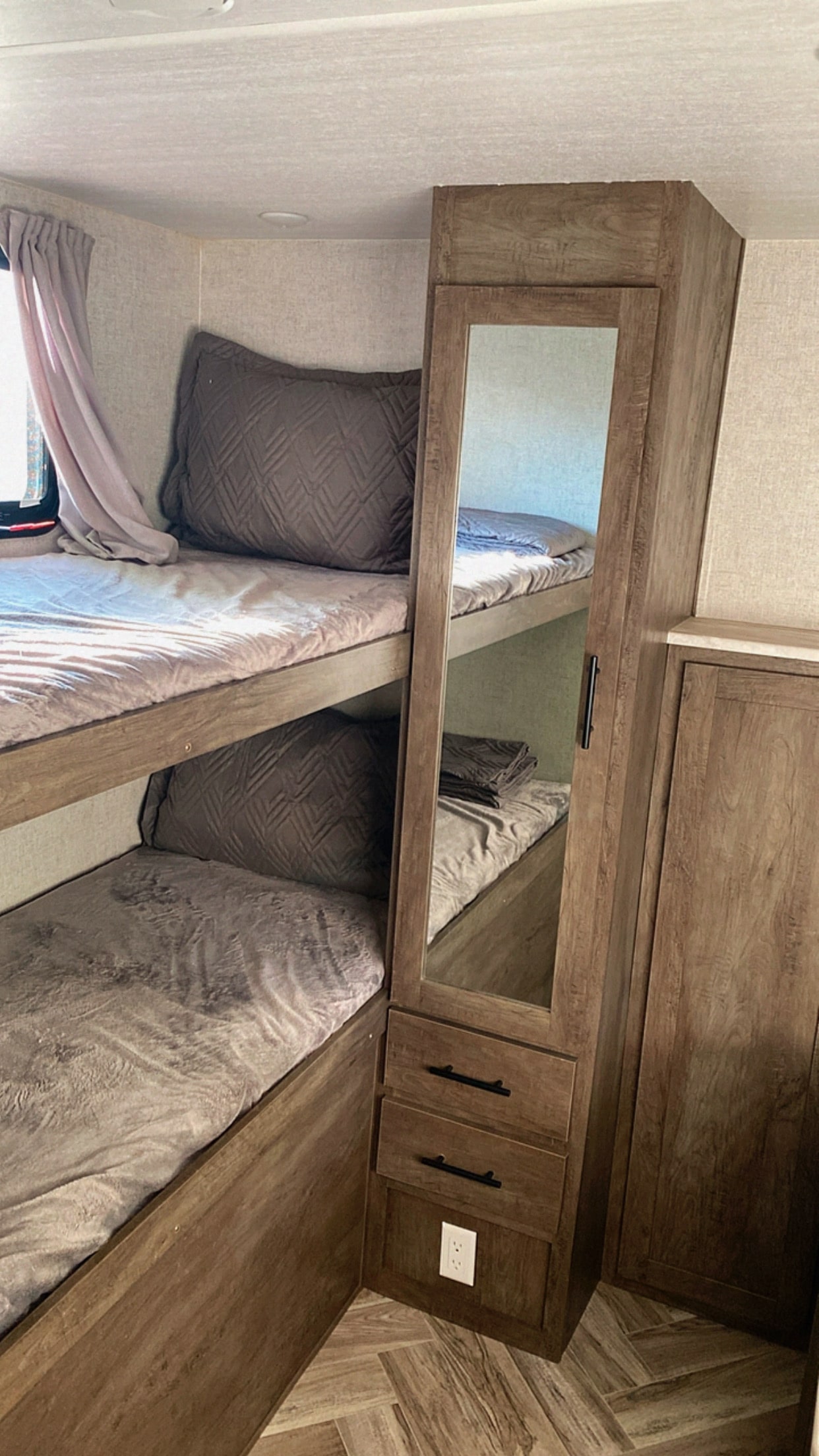Wood-paneled RV rental interior features comfy bunk beds, built-in storage with a mirror, and a wall outlet.. Forest River Salem 2021