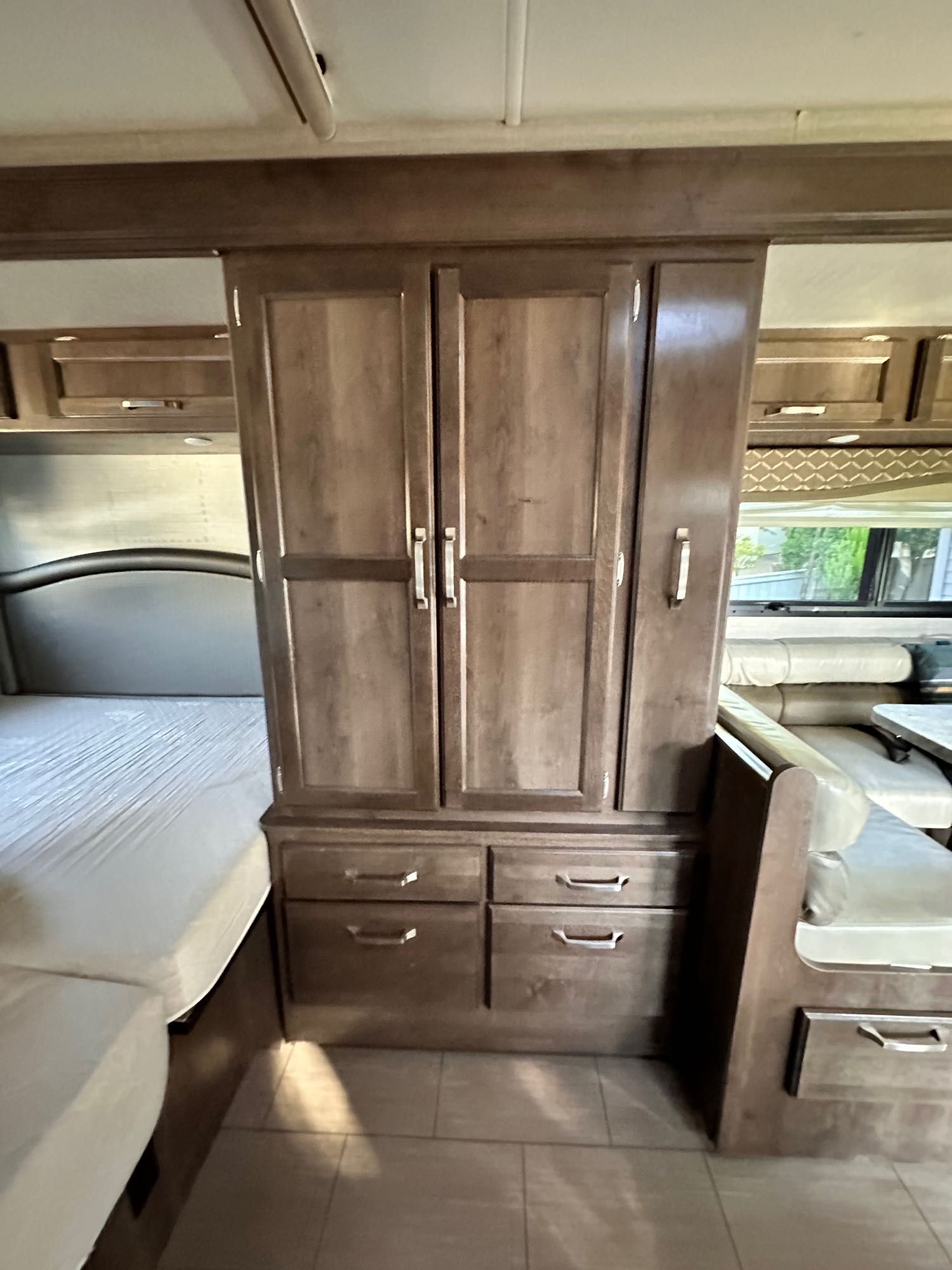 RV rental interior featuring a central storage cabinet, bed, and dinette area, offering comfortable living space.. Jayco Melbourne 2018