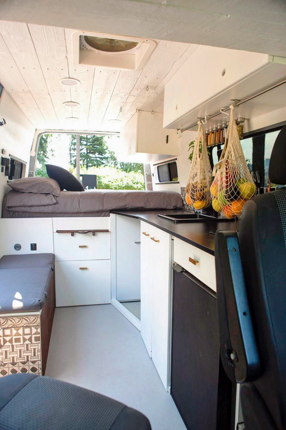 Bright RV rental interior featuring a white wood ceiling, grey bed, dark kitchen, and smart storage maximizing space for travel.. Mercedes-Benz Sprinter 2012