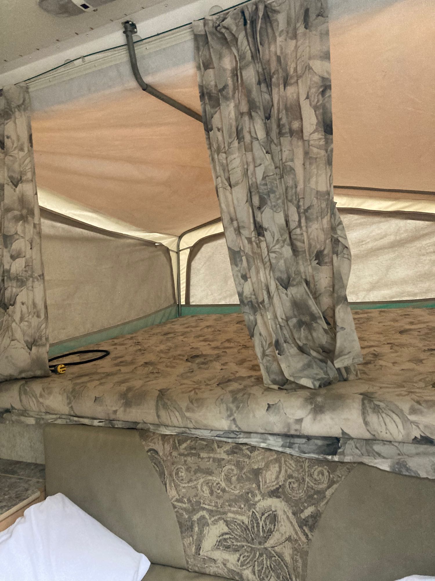 Experience comfort in this RV rental's pop-up sleeping area, featuring patterned bedding and privacy curtains.. Starcraft Starcraft Popup Trailer 2004