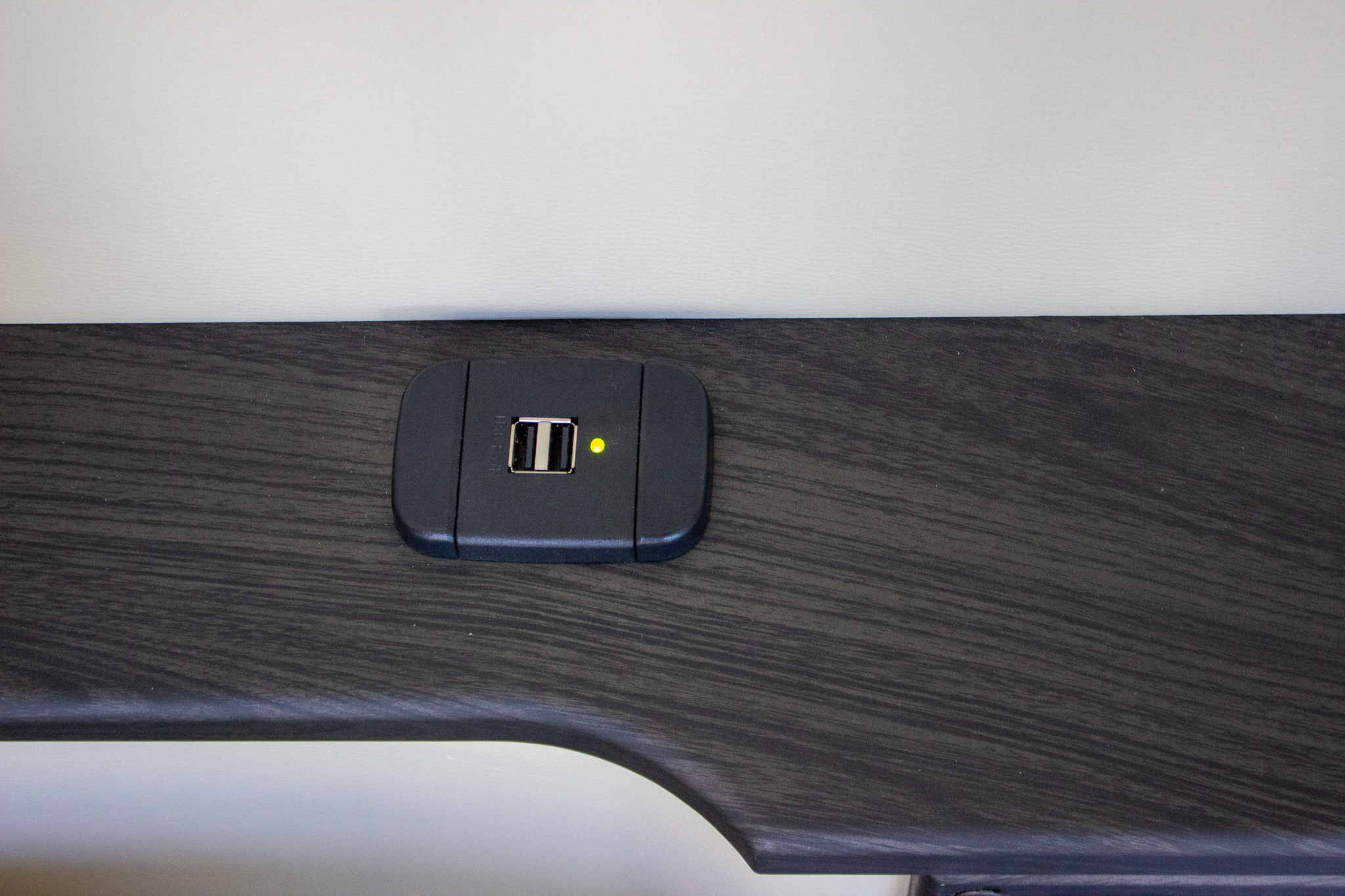 Close-up of a dual USB charging port with a yellow power indicator in an RV rental. Charge your devices easily.. Midwest Automotive Designs Ultimate CamperVan 2023