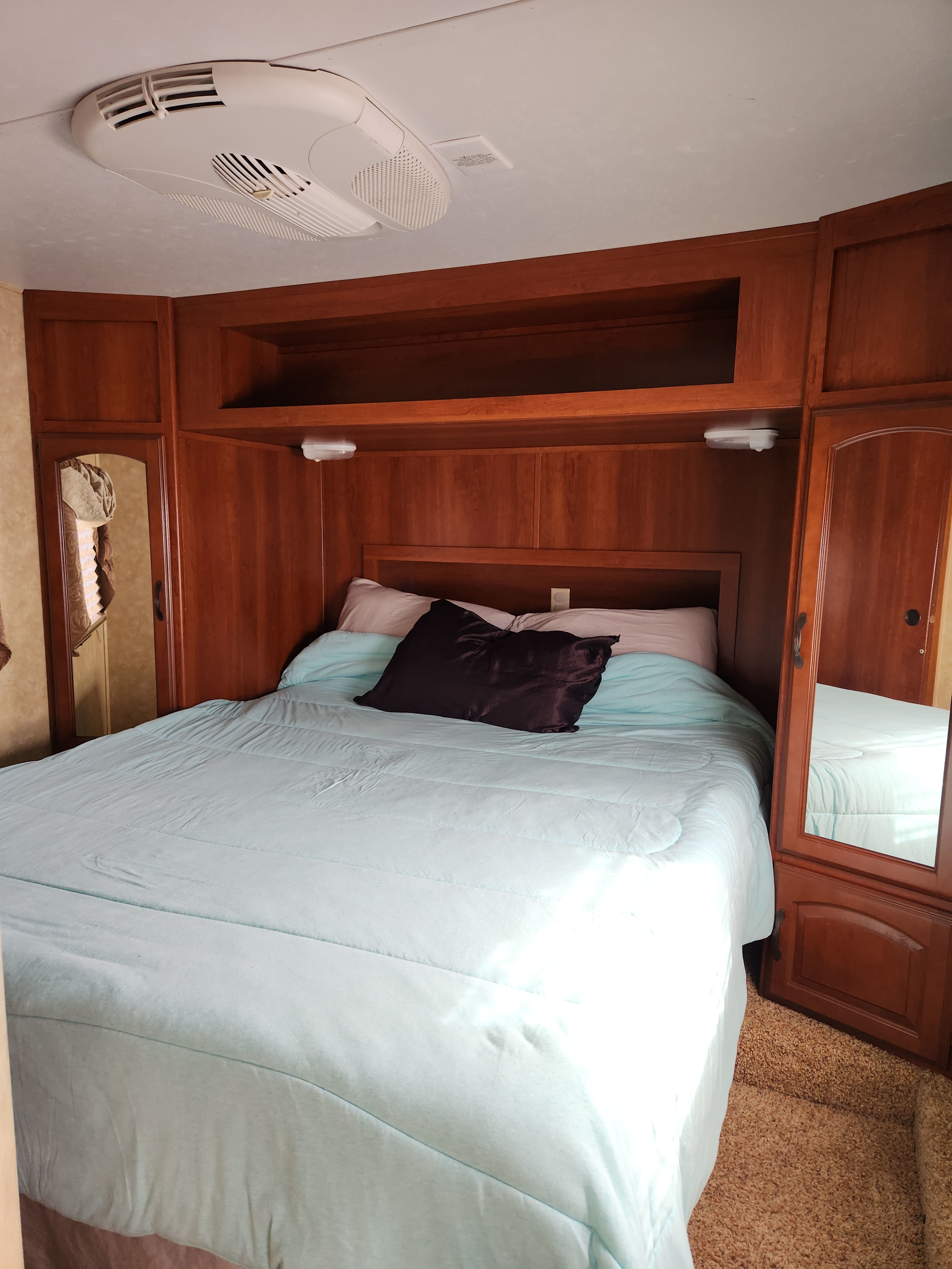 Cozy RV rental bedroom with wooden cabinetry, a comfortable bed, and overhead AC unit.. Forest River Salem Hemisphere Lite 2012