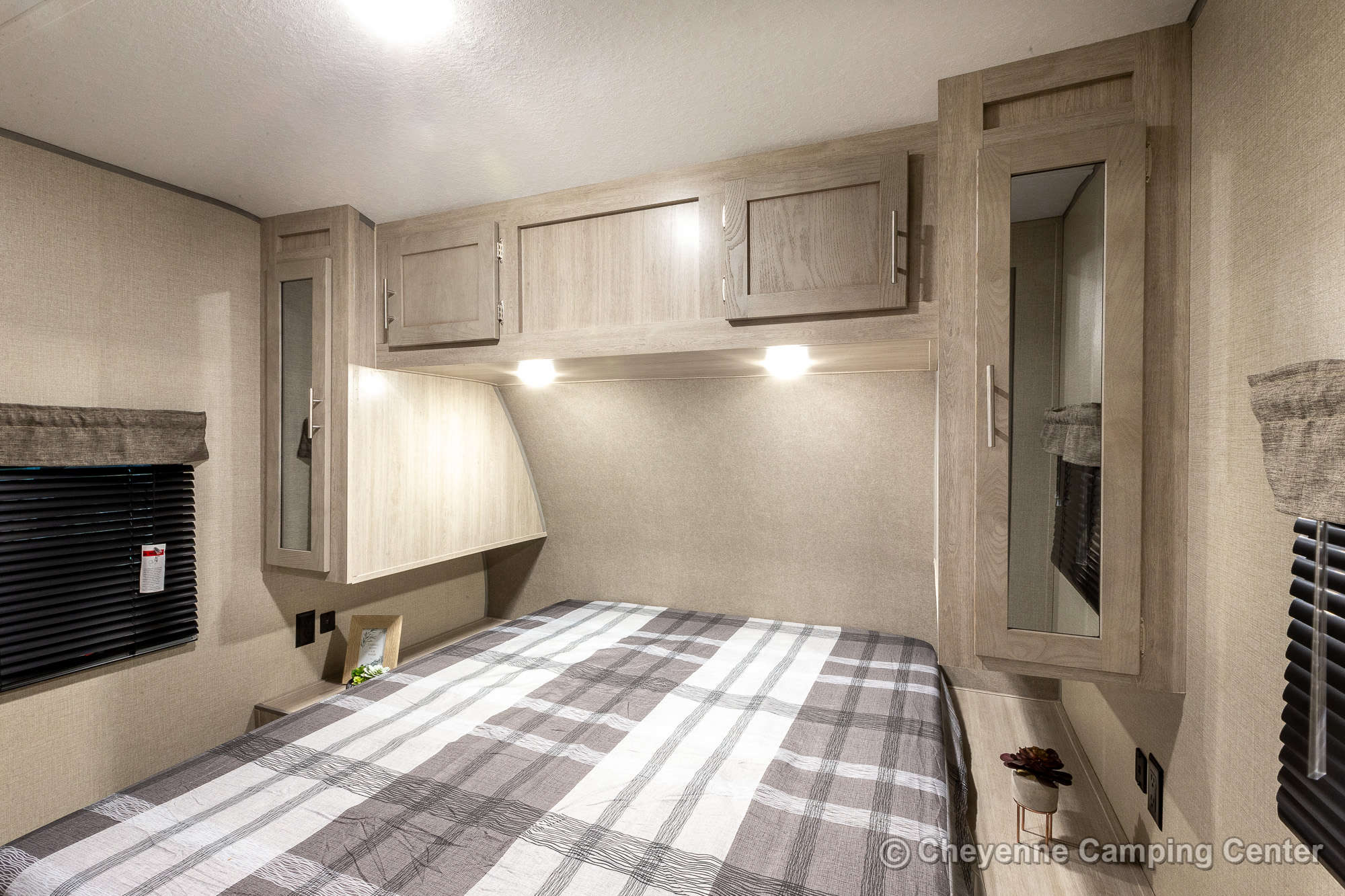 RV rental's cozy bedroom features a queen bed, overhead cabinets, and mirrored wardrobes.. Coachmen Catalina 2022