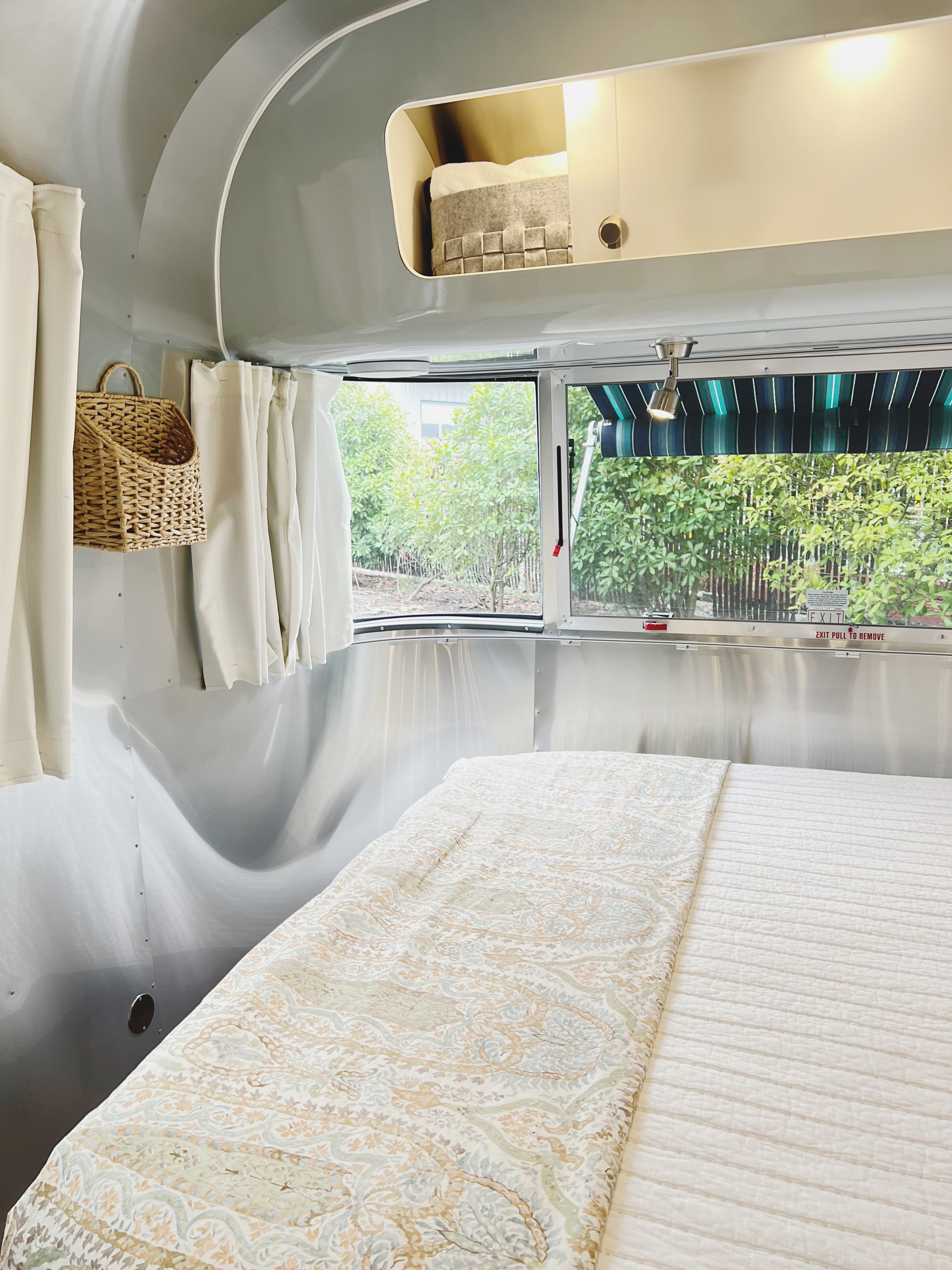 Cozy RV rental bedroom featuring a metallic Airstream interior, comfortable bed, and a scenic window view.. Airstream International 2022