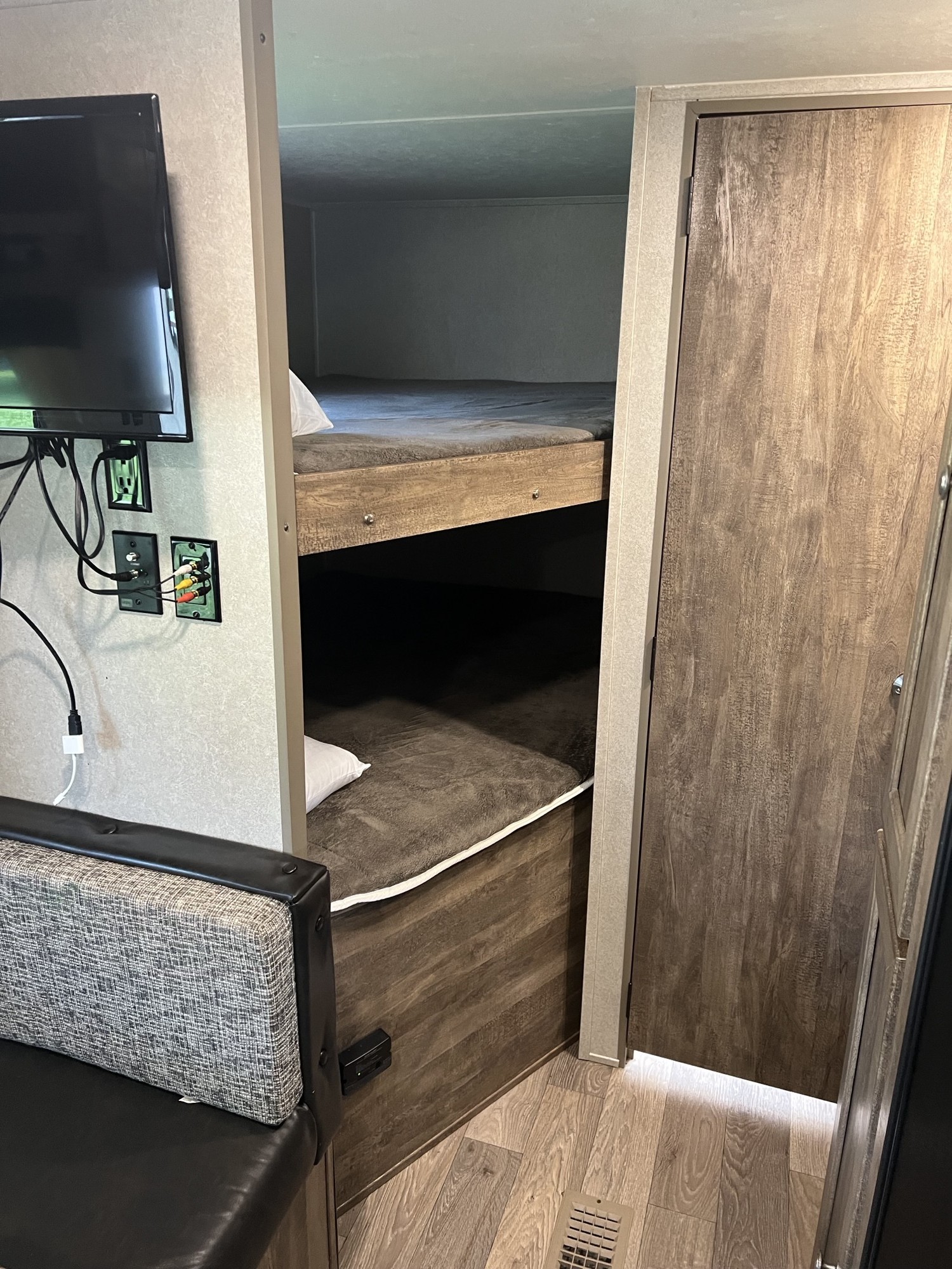 Inside this RV rental: bunk beds with grey bedding, a wall-mounted TV, and a nearby upholstered bench.. Forest River Palomino Puma XLE 2018