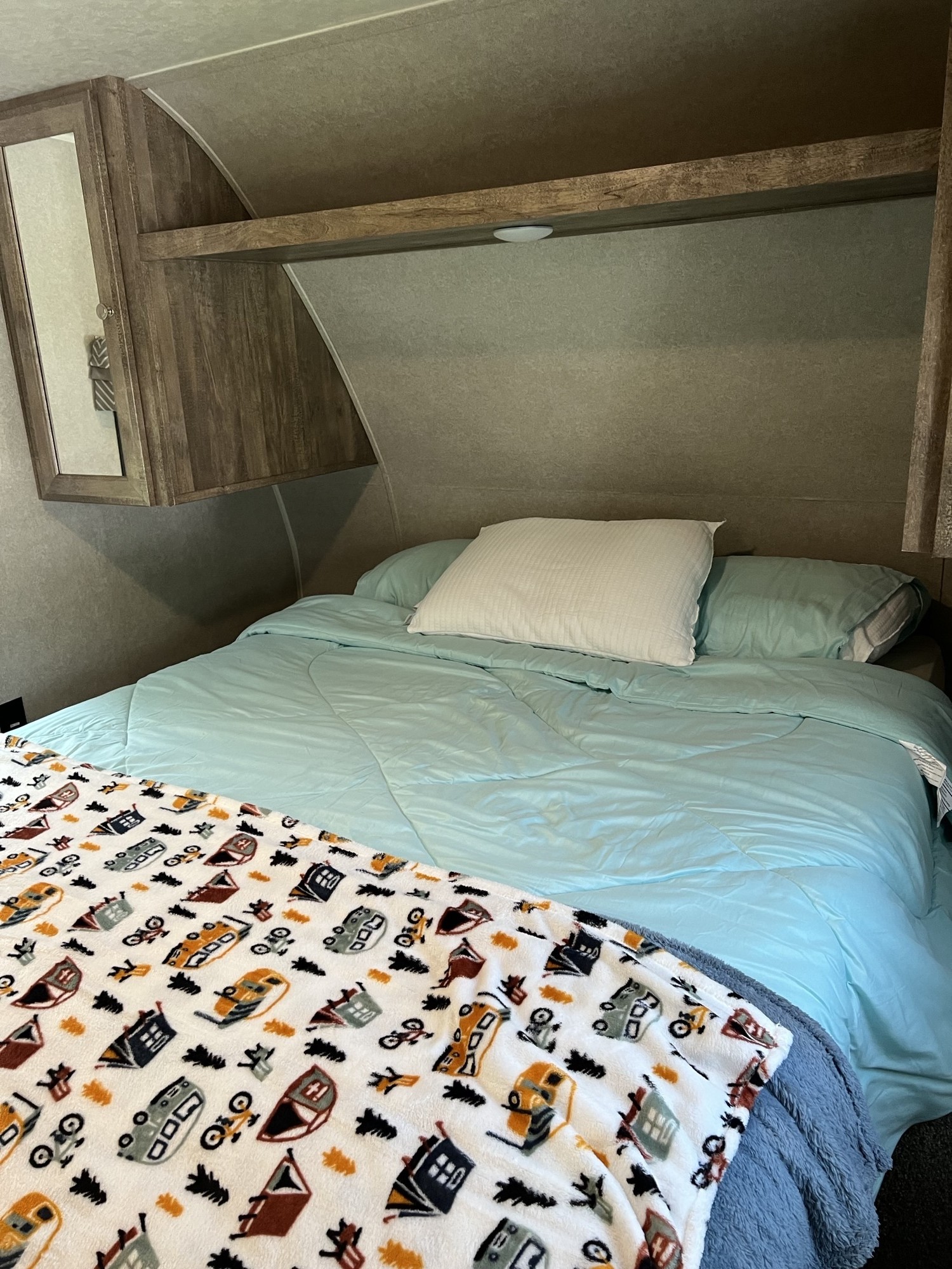 Cozy RV rental bedroom with light blue bedding, a fun vehicle blanket, and storage cabinets.. Forest River Palomino Puma XLE 2018