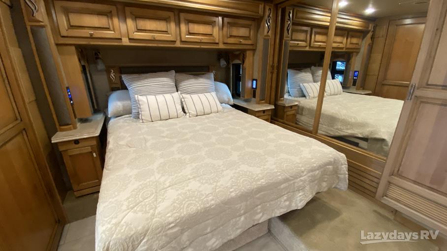 Inside an RV rental: a cozy bedroom featuring a comfortable bed, overhead cabinets, and mirrored closet.. Tiffin QKH 2018