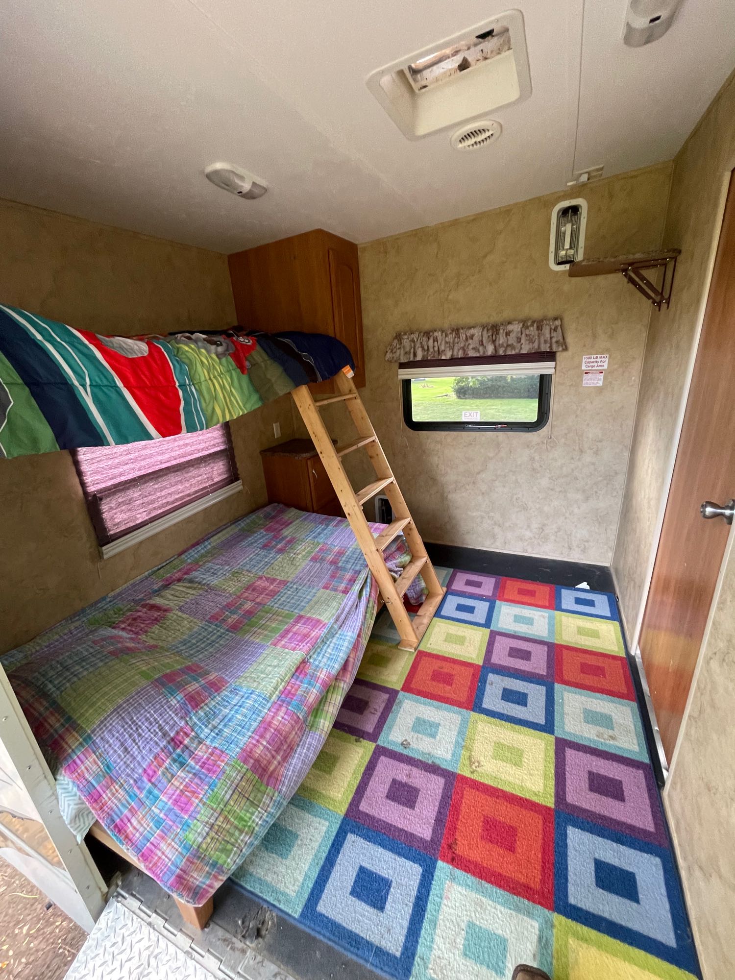 RV rental bunkhouse: bright, playful interior with colorful rug, bunk beds, ladder, window, and storage. Ideal for families.. Keystone RV Cougar 2012