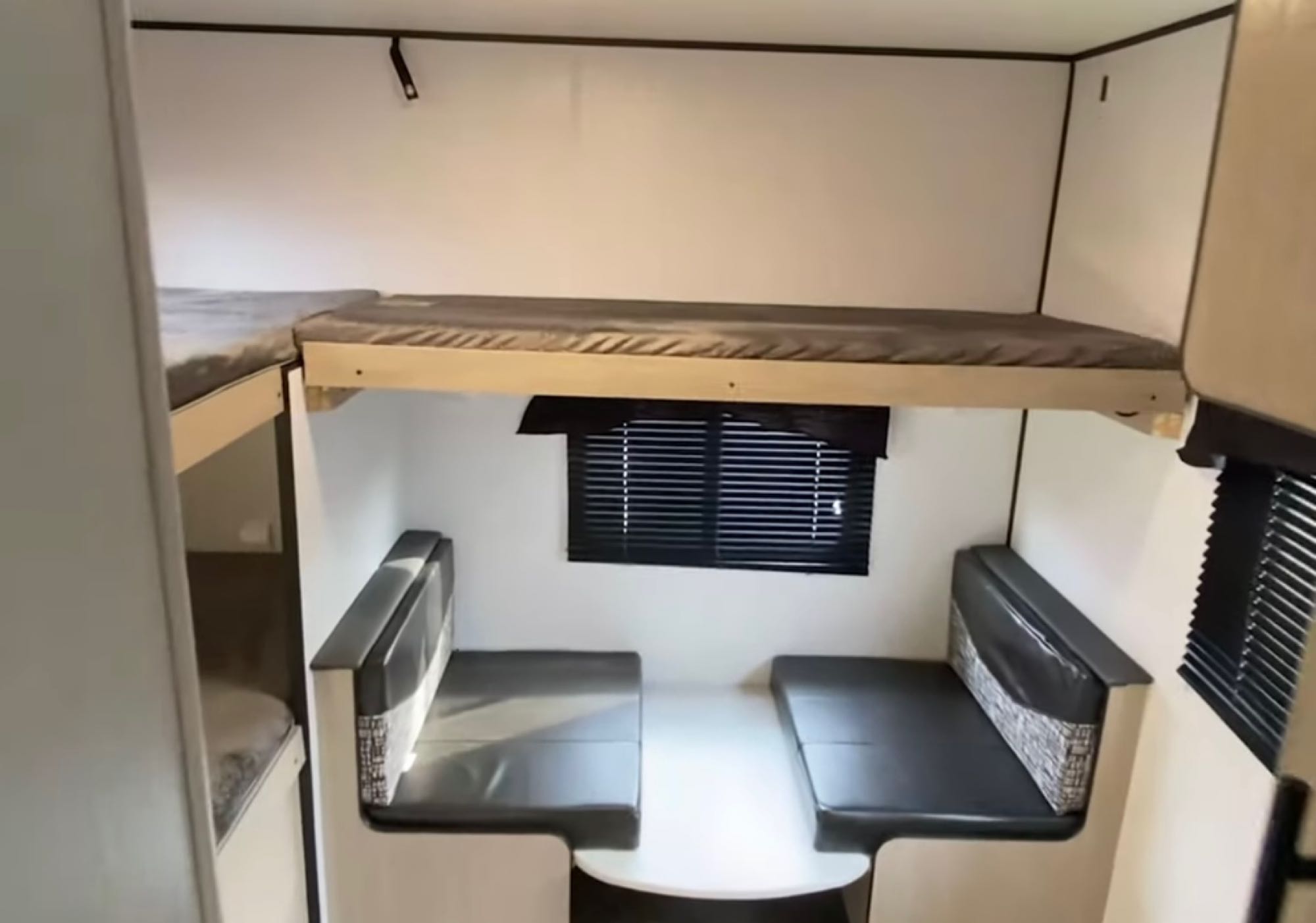 This RV rental interior features a cozy dinette with seating, ample bunk beds for sleeping, and a window with blinds.. Heartland RVs Prowler 2022
