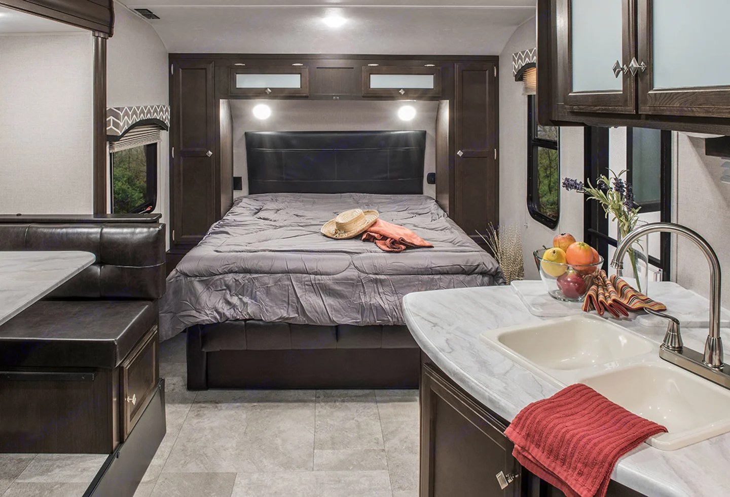 Inside a comfortable RV rental: bed, kitchen sink, and dining booth with windows. Ready for your next journey!. Sonic Sonic Trailer 2019