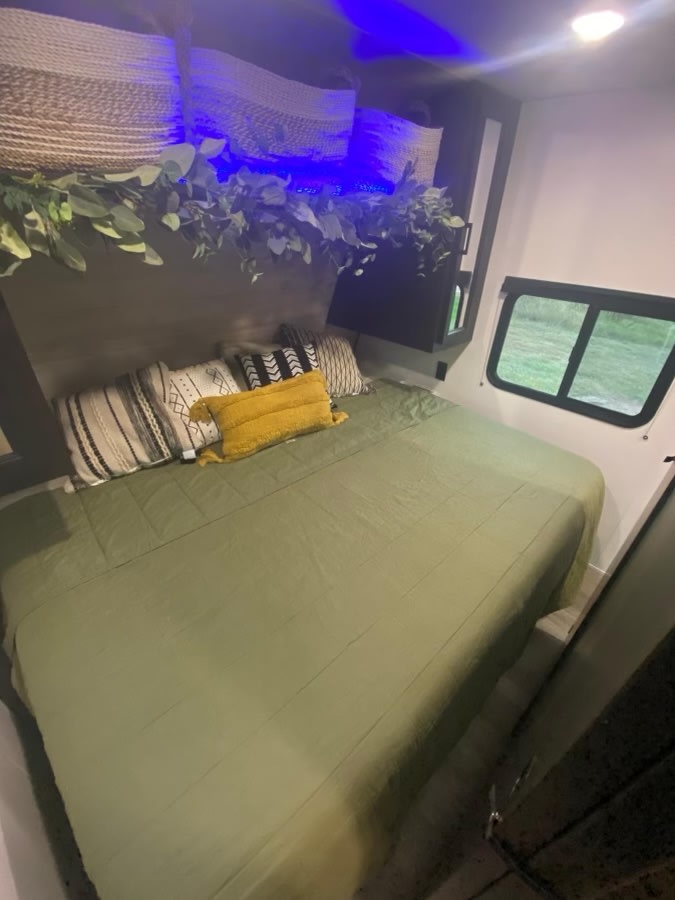 Stylish RV rental bedroom interior with a green bed, accent pillows, woven baskets, and LED greenery.. Jayco Jay Flight 2022