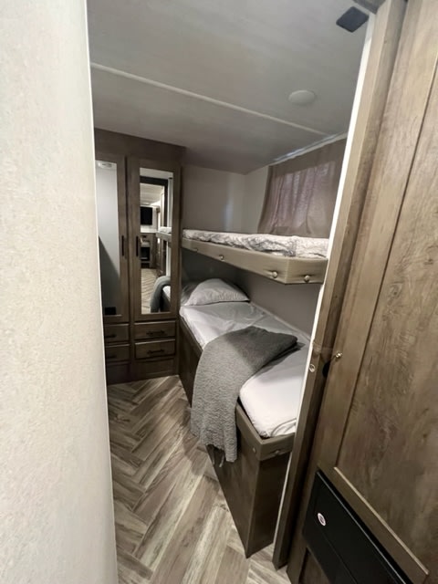 Cozy RV rental bunk beds, perfect for family travel. Features a built-in wardrobe and wood-look flooring.. Forest River Salem Cruise Lite 2021