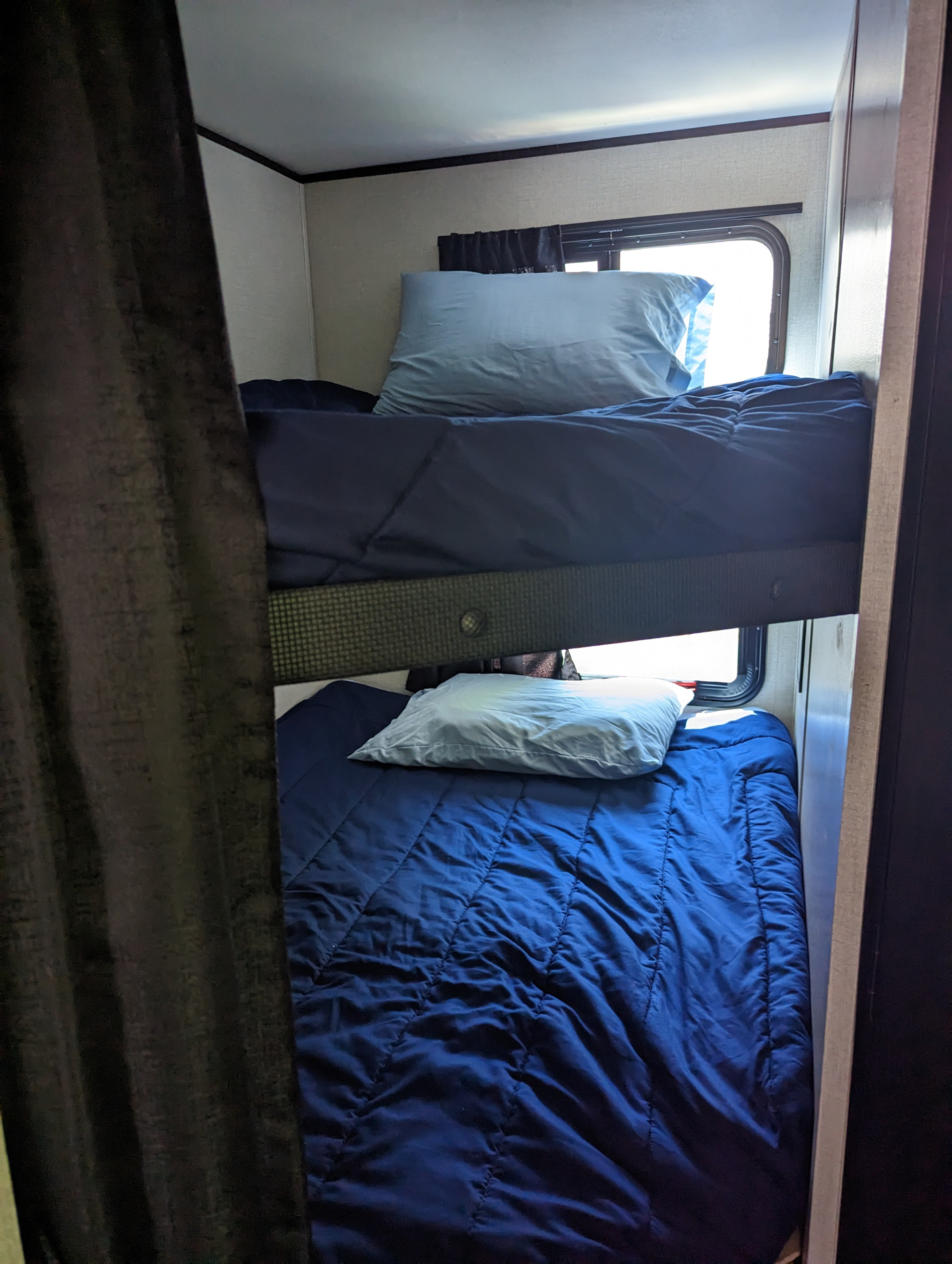 Two neatly made bunk beds with blue bedding in an RV rental interior.. Starcraft Autumn Ridge 2022