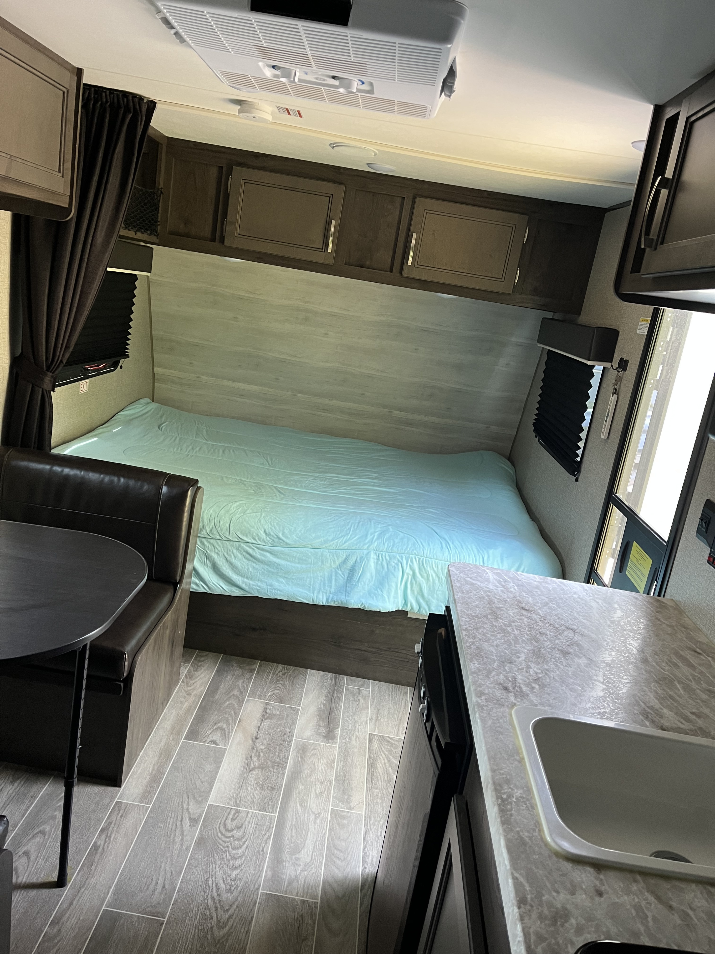 RV rental: Compact interior with a bed, dinette, and kitchenette. Features wood-look floors and overhead storage.. Jayco Jay Flight SLX 2020