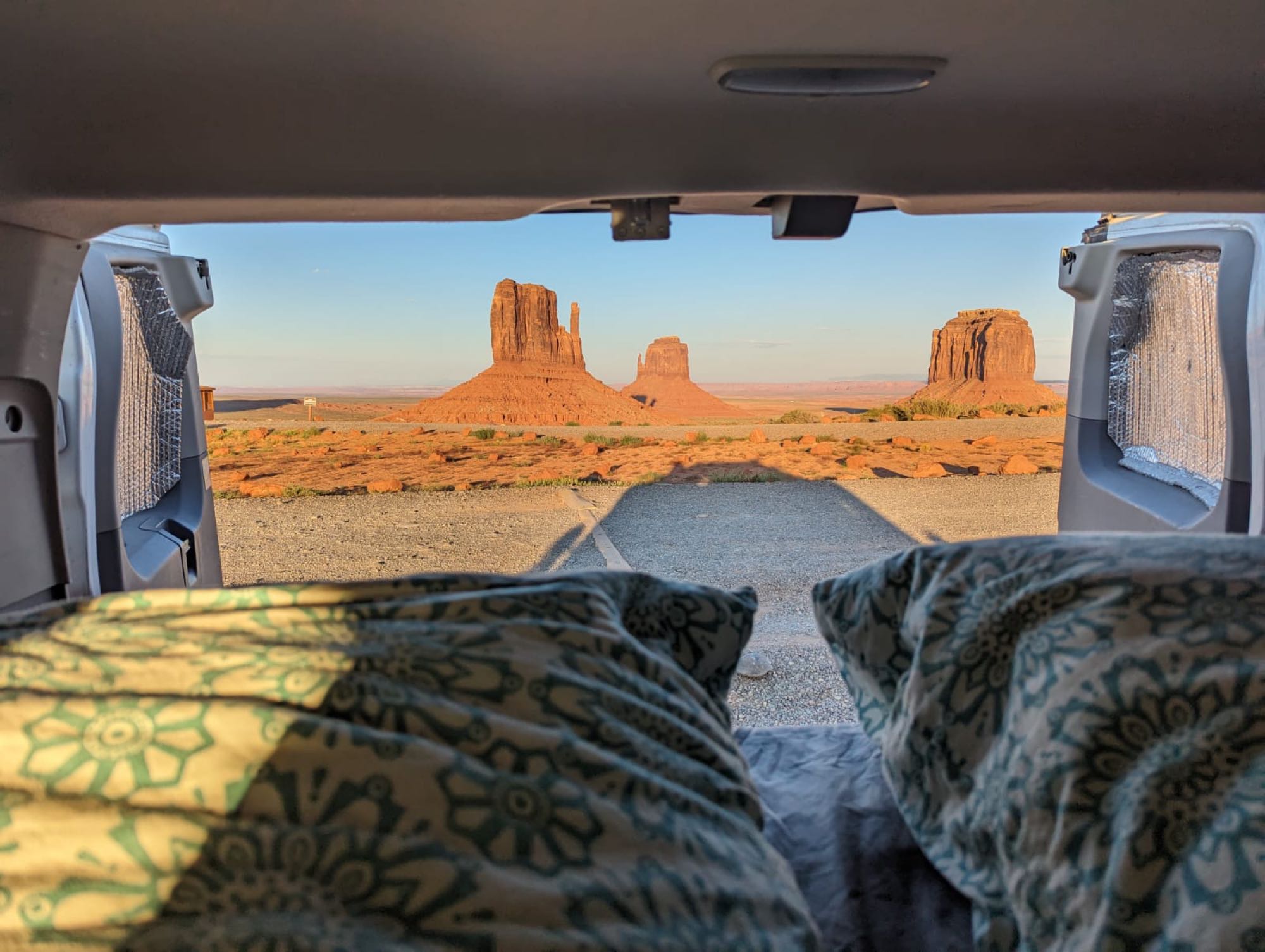 RV rental: Iconic Monument Valley red rock formations glow in golden light, viewed from inside a vehicle's bed.. Ford Transit 2016