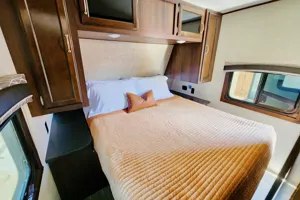 Spacious RV rental bedroom with a comfortable queen bed, ample wood cabinets, and windows. Your cozy travel home!. Jayco Jay Flight 2021