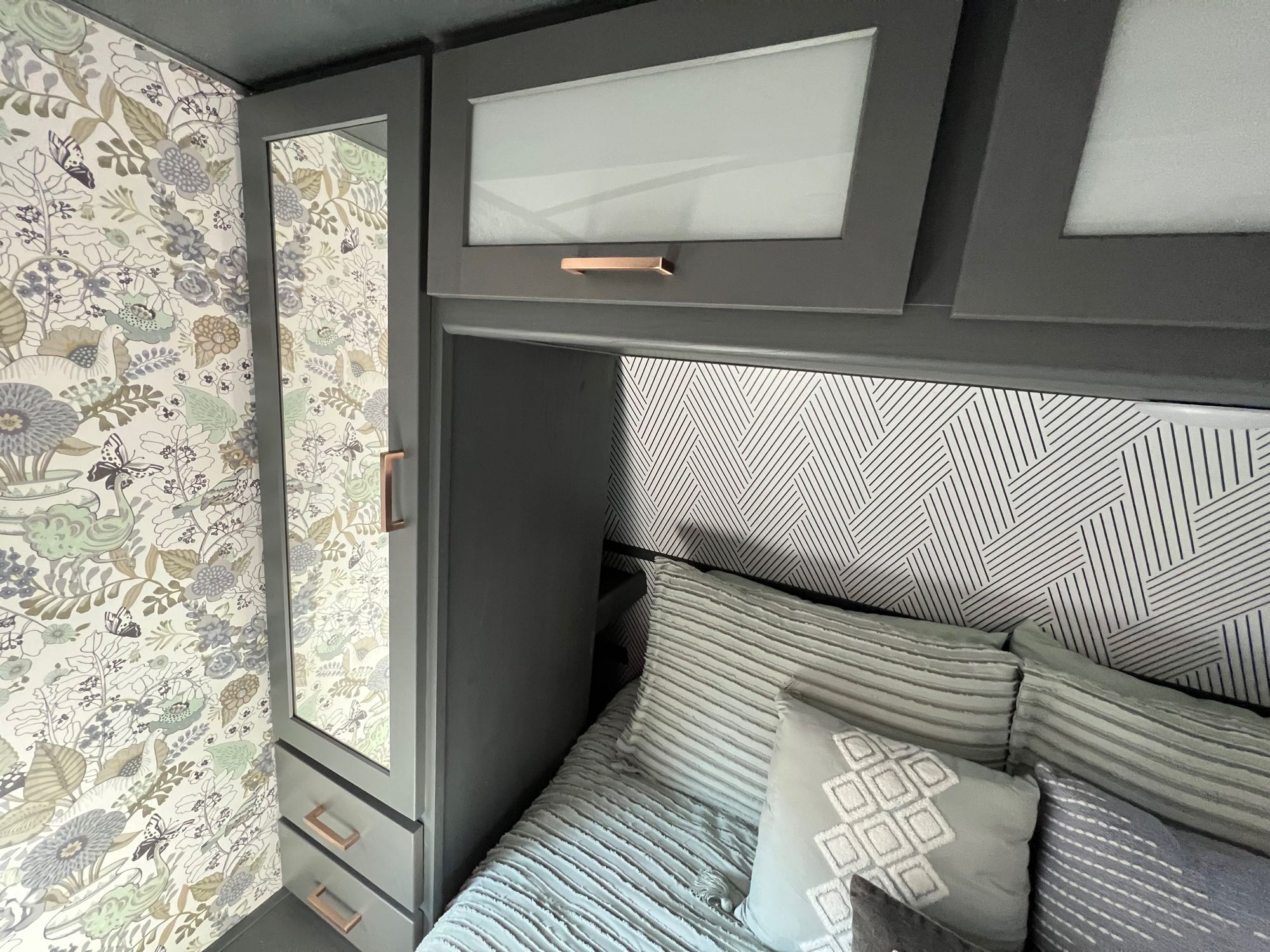 Stylish RV rental bedroom with modern gray cabinets, mirrored closet, patterned wallpaper, and cozy bedding.. Keystone RV Bullet Ultra Lite 2022