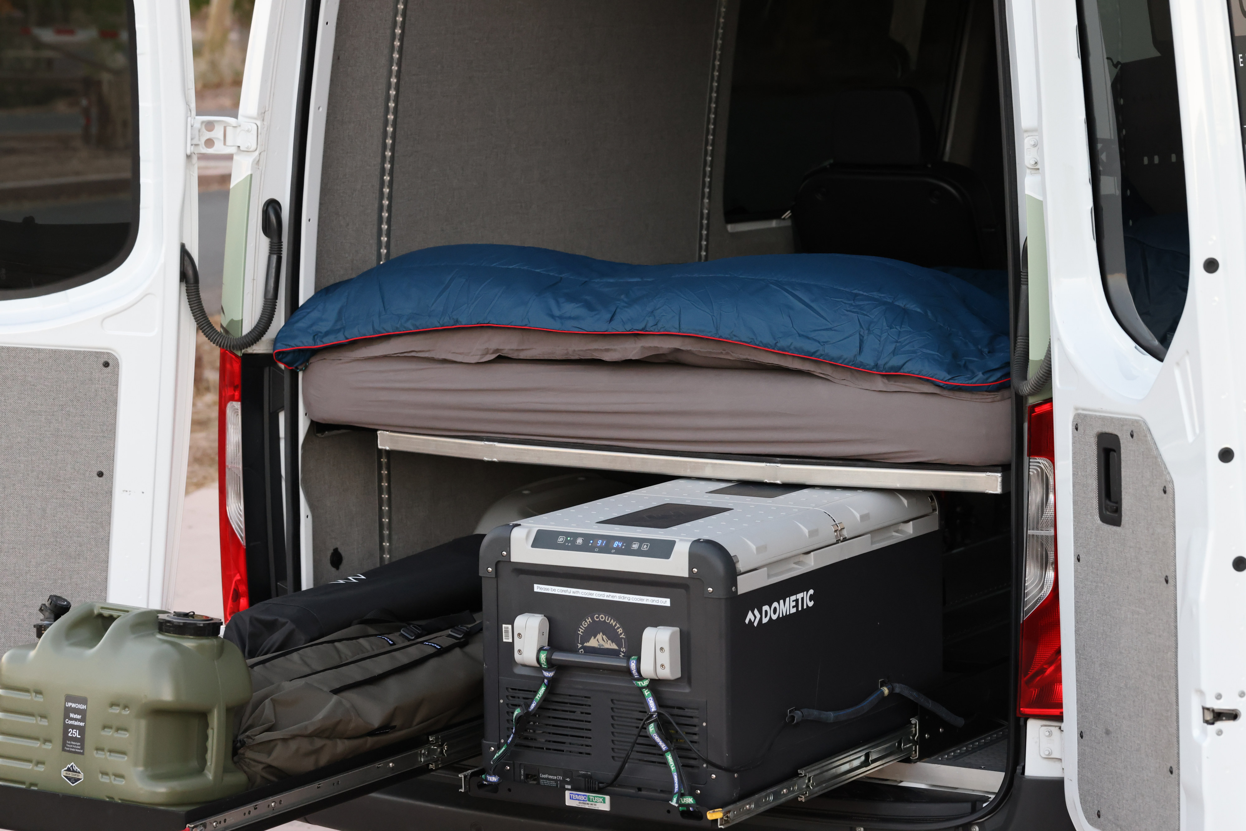 This RV rental's rear setup offers a comfortable bed, Dometic cooler, and water storage for off-grid adventures.. Mercedes Benz Sprinter 2019