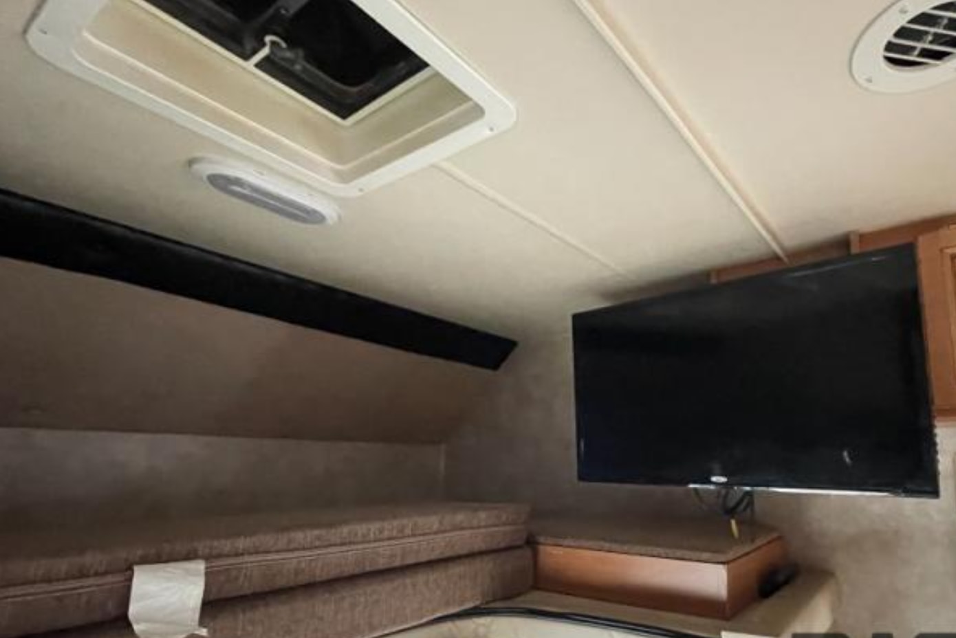 Inside this RV rental, a mounted TV, ceiling vents, and stacked cushions for a bunk area create a cozy, functional space.. Nexus RV Phantom 2017
