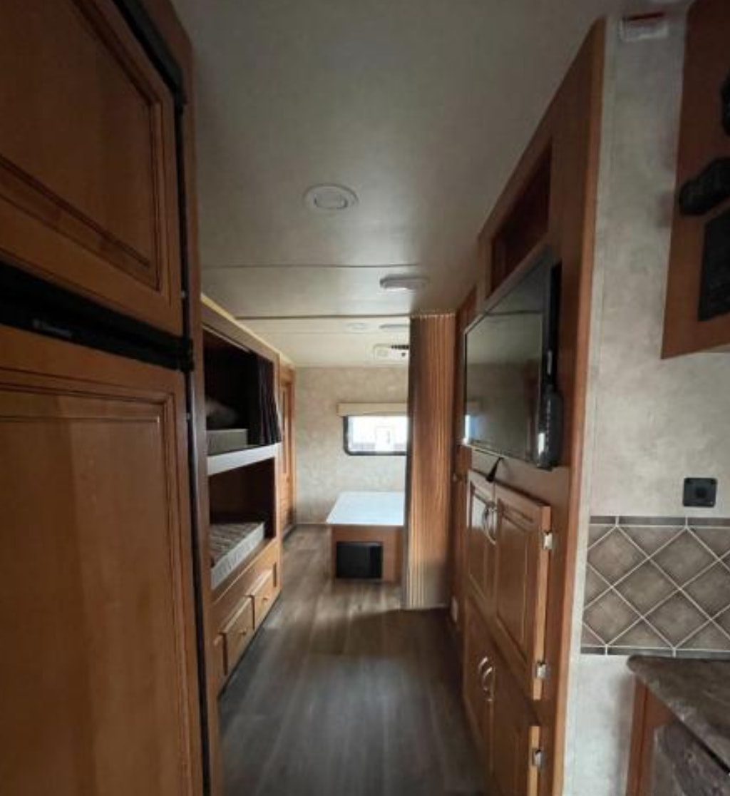 This RV rental's interior features bunk beds, a TV, kitchen, and dinette, providing a full mobile living space.. Nexus RV Phantom 2017