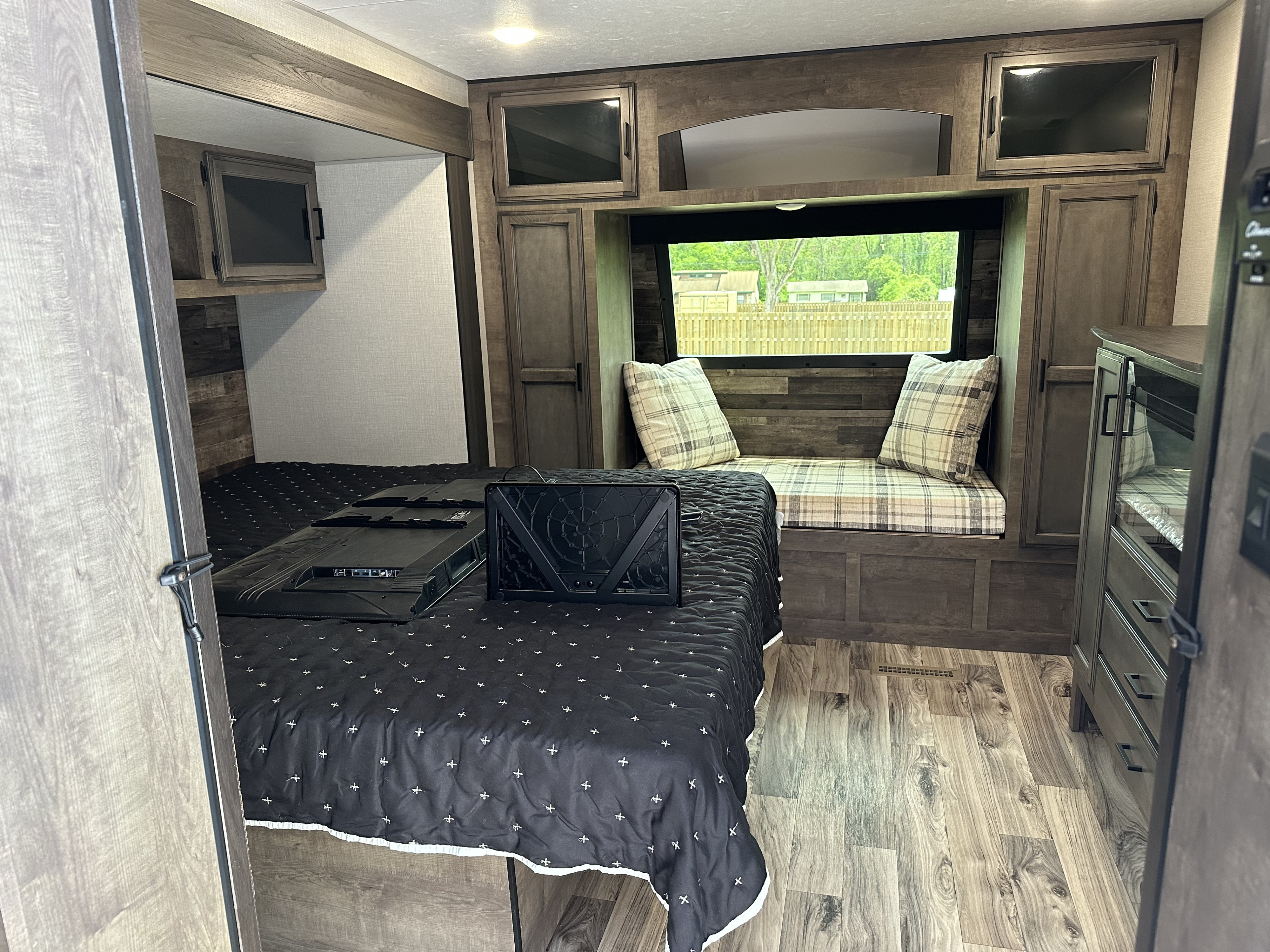 Inside a modern RV rental bedroom featuring a bed, ample storage, a scenic window seat, and a TV for entertainment.. Sport Trek Touring 2021