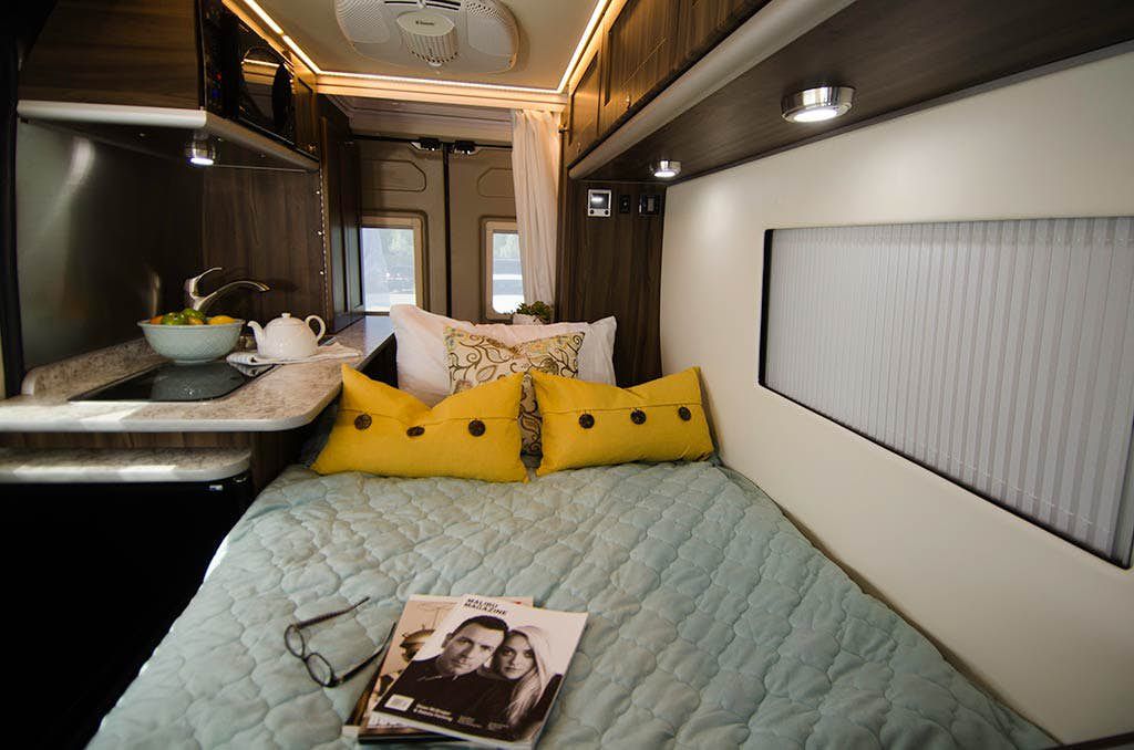 Step inside a comfortable RV rental: compact kitchen, cozy bed with bright pillows, and convenient overhead storage.. Carado Carado Class B 2017