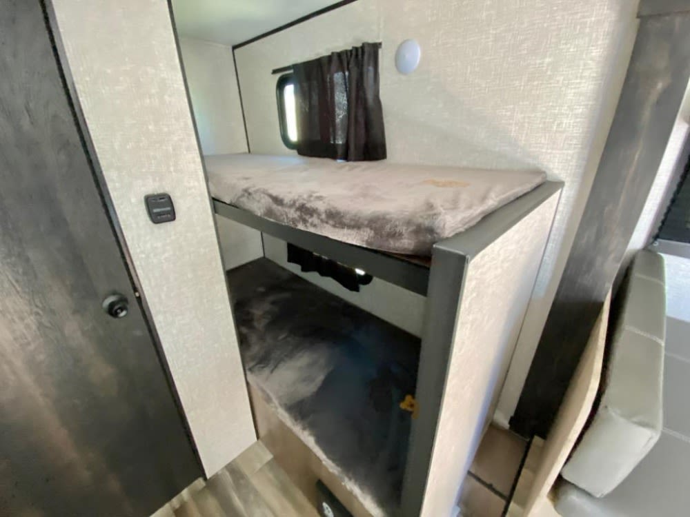 Inside an RV rental: cozy bunk beds, a perfect sleeping area for your next recreational vehicle adventure.. Starcraft Autumn Ridge 2023
