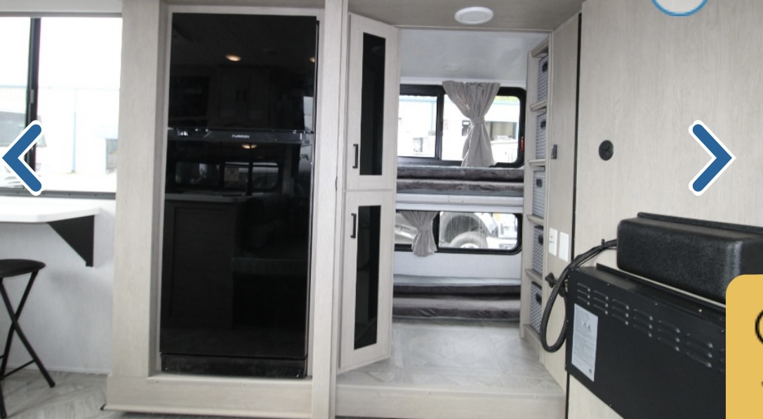 RV rental interior: light-colored walls, bunk beds, compact kitchen with fridge, and small desk.. Forest River Wildwood XLite View 2024