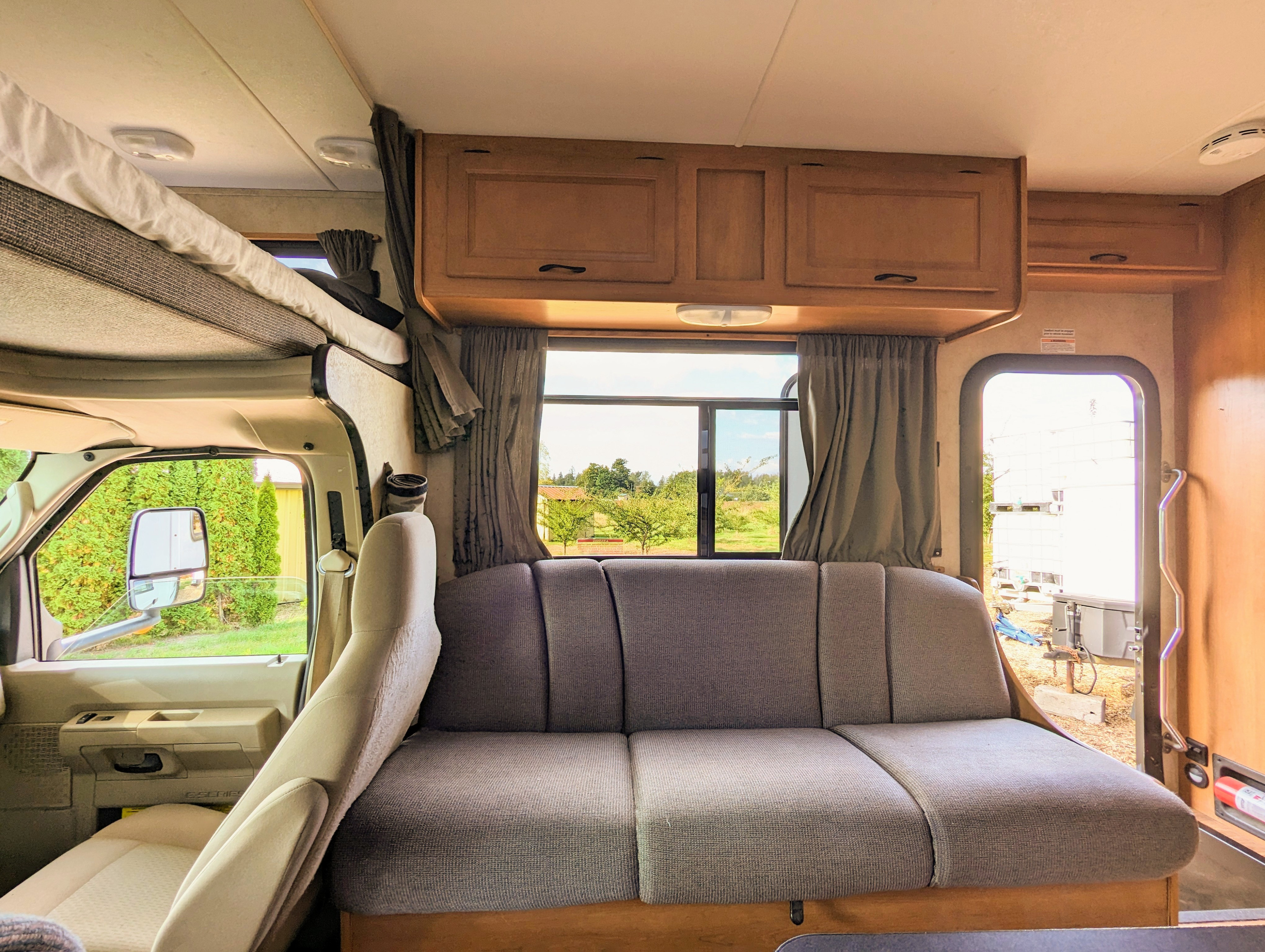 Bright RV rental interior with a cozy sofa, functional overhead bunk, and storage. Ideal for road trips.. Thor Majestic 2012