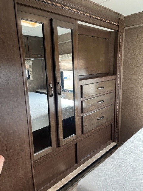 RV rental bedroom: dark wood wardrobe with mirrored doors, dresser drawers, and hanging space for ample storage.. Thor Freedom Elite 2017