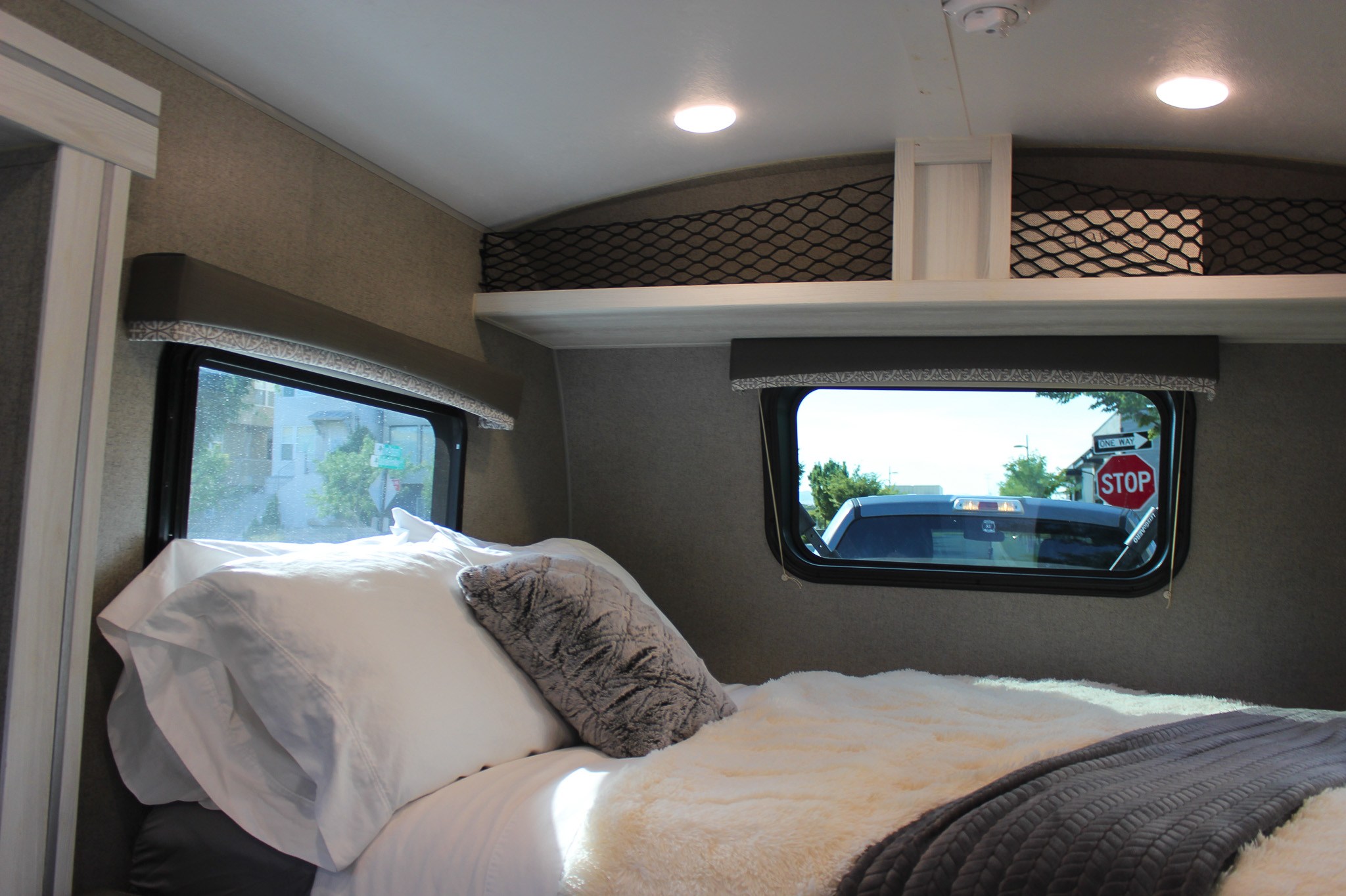 Inviting RV rental bedroom with a comfortable bed, two windows for views, and convenient overhead storage nets.. Forest River Rockwood GeoPro 2019