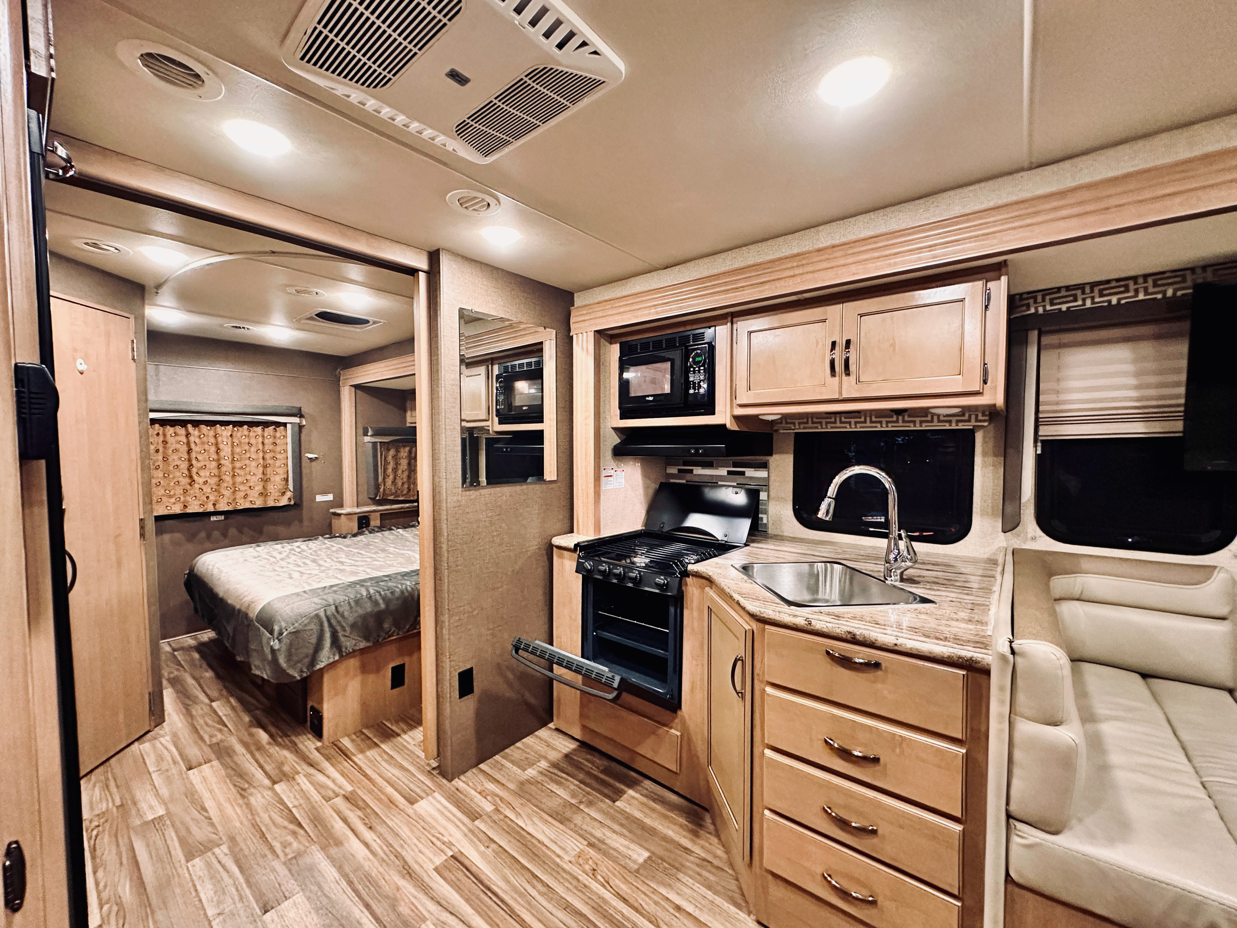 Experience this RV rental's modern interior: full kitchen (stove, sink, microwave, cabinets), wood floors, comfy bed, and lounge.. Thor A.C.E. 2018