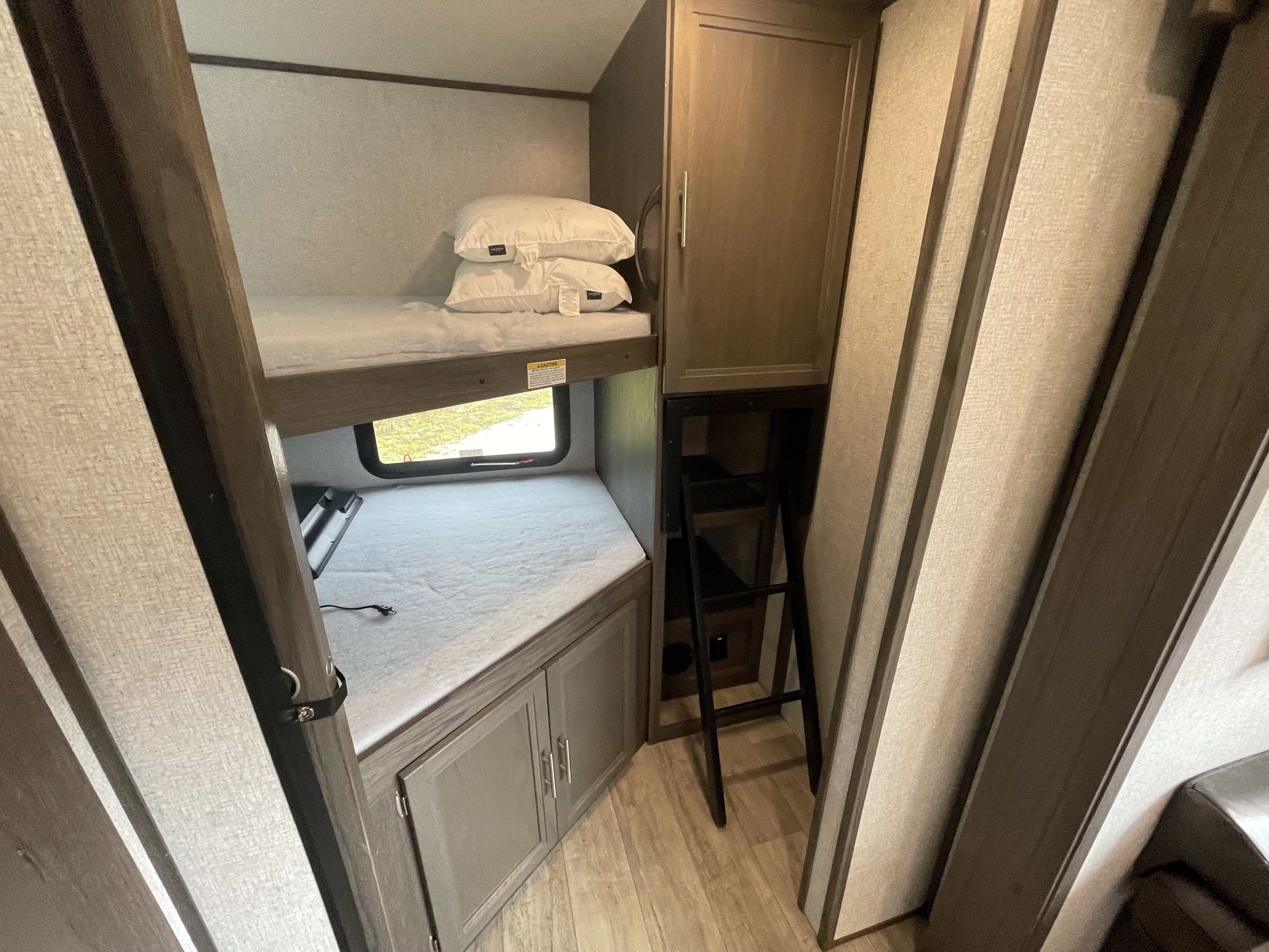 Cozy RV rental bunk beds with window view, storage, and access ladder. Ideal for family trips.. Dutchmen Kodiak Ultra Lite 2021
