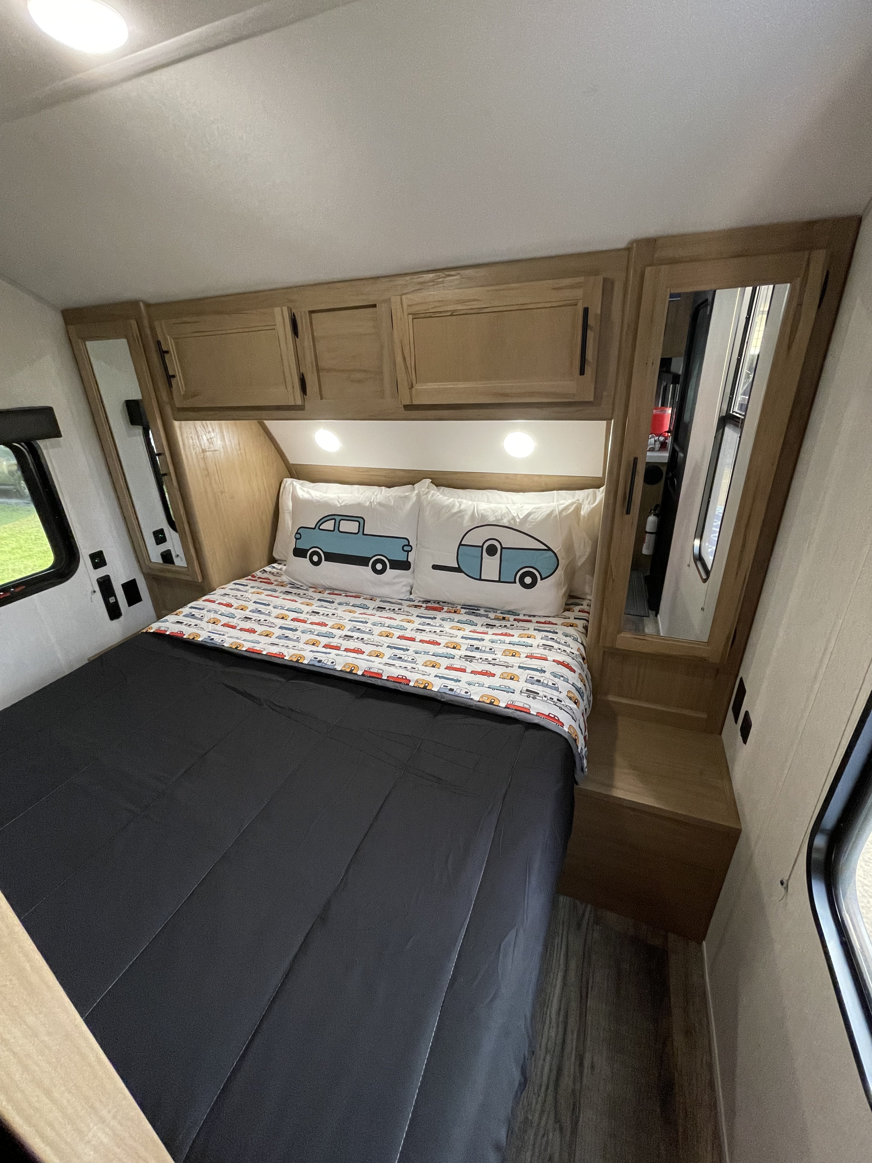 Cozy RV rental bedroom with truck & camper pillows, overhead storage.. Forest River Cherokee Grey Wolf 2023