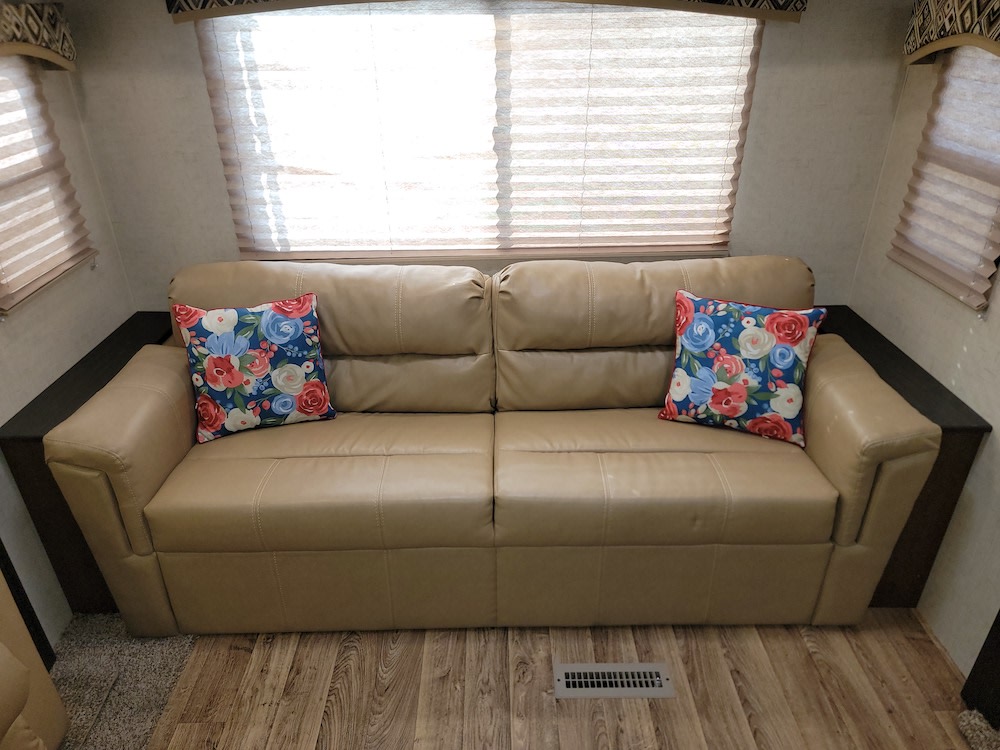 Cozy RV rental living area featuring a comfortable tan sofa and two vibrant floral cushions.. Sport Trek Sport Trek Trailer 2017