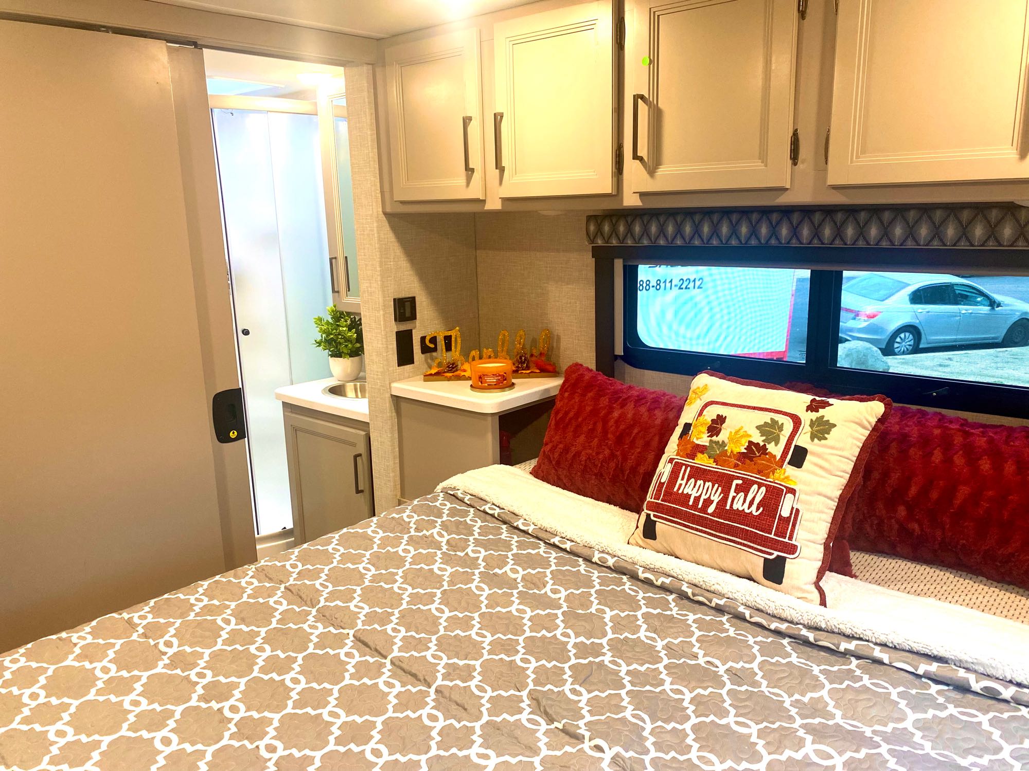 Cozy RV rental bedroom with fall decorations, a compact bathroom, and convenient counter space.. Thor Quantum 2023