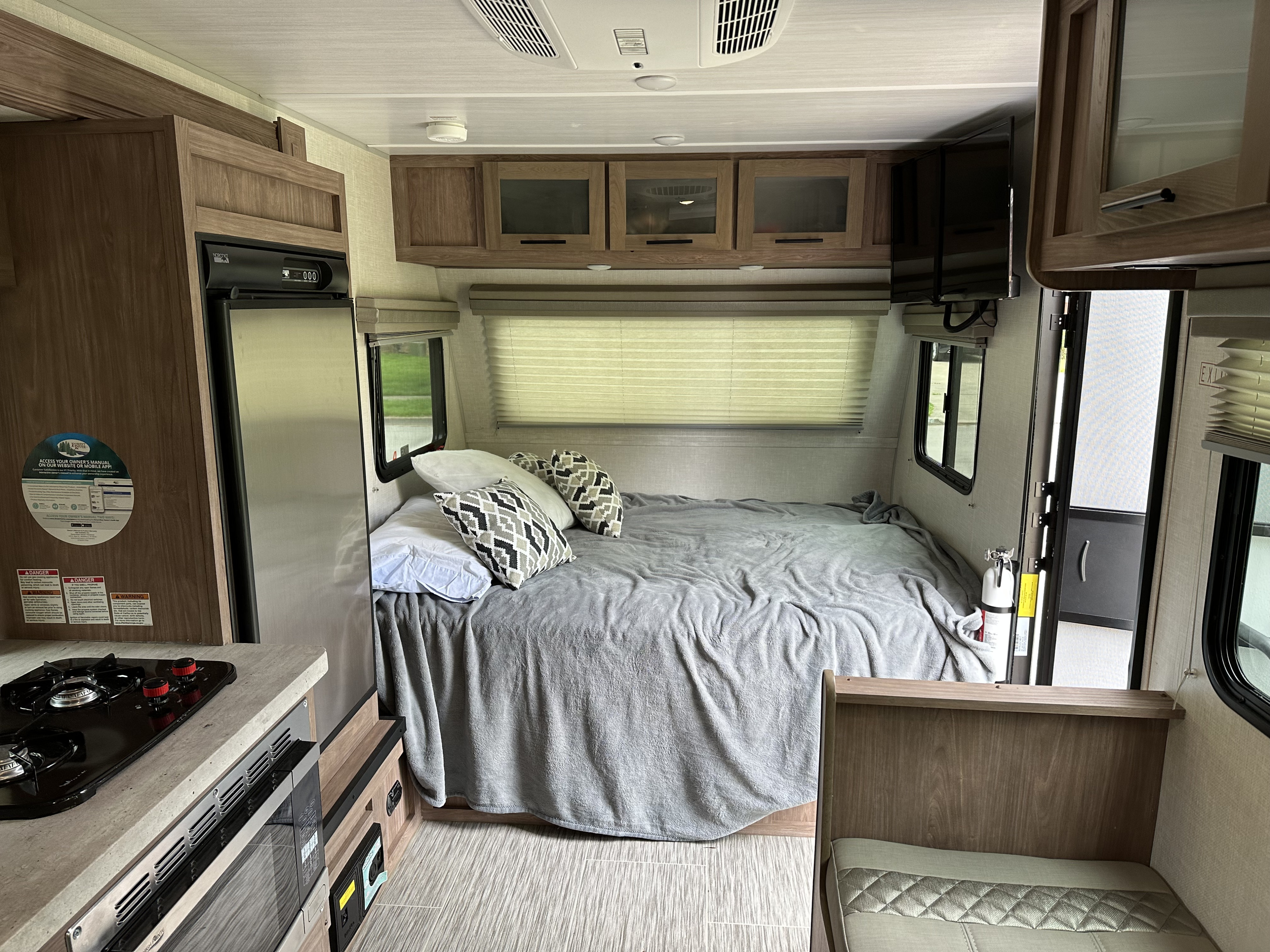 Inside an RV rental, featuring a comfortable bed, compact kitchen, overhead cabinets, and a television, ready for your trip.. Forest River NoBo 2022