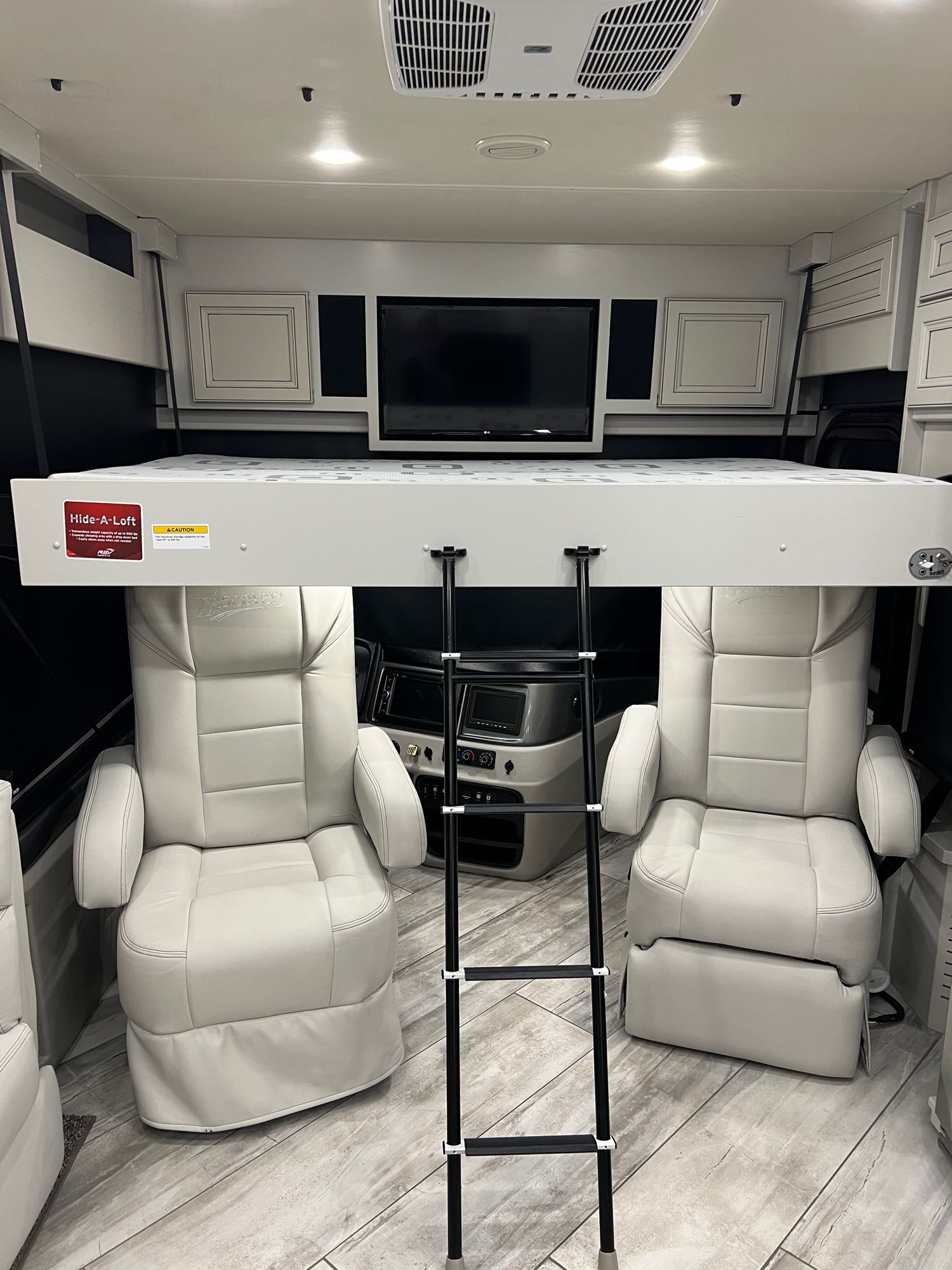 RV rental interior: Lowered Hide-A-Loft bunk bed, ladder, and two captain's chairs provide flexible space.. Fleetwood Discovery 2022