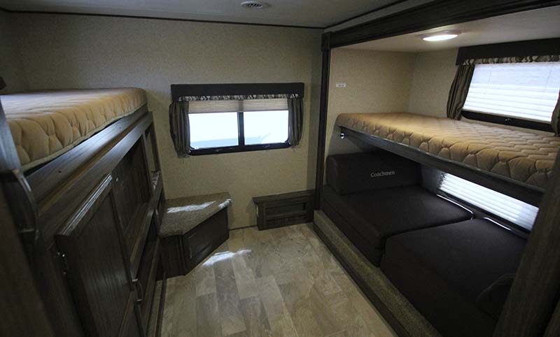 This RV rental shows a bunkhouse with upper beds, a lower convertible sofa-bed, and a window.. Coachmen Apex 2018