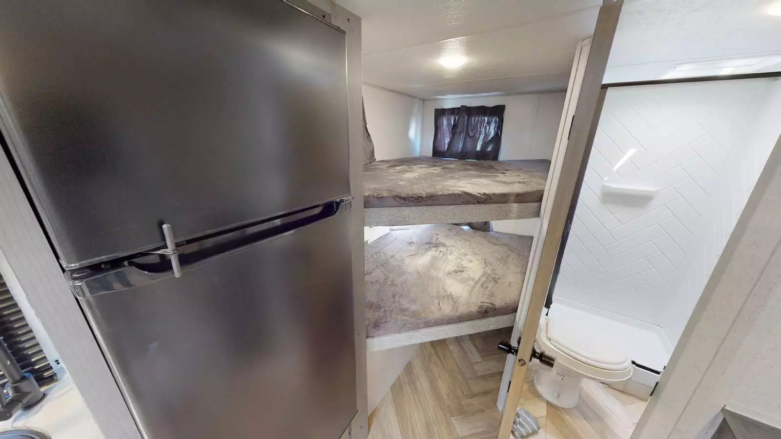 This RV rental features a fridge, two bunk beds, and a compact bathroom with a shower and toilet. Ready for your adventure.. Ozark Ascent 2023
