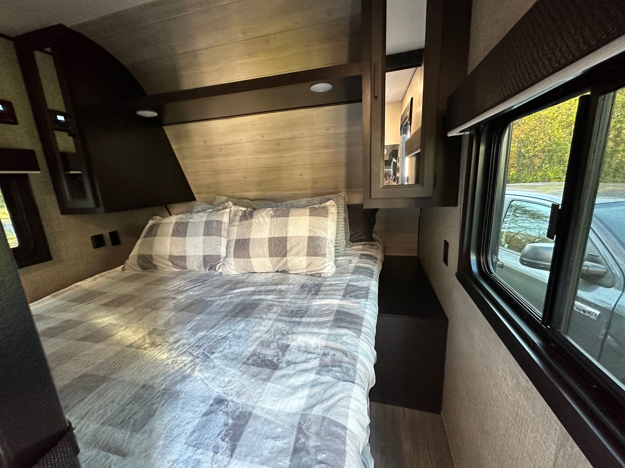 Cozy RV rental bedroom with plaid bedding, overhead storage, and a window view. Perfect for travel comfort.. Jayco Jay Flight SLX 2022